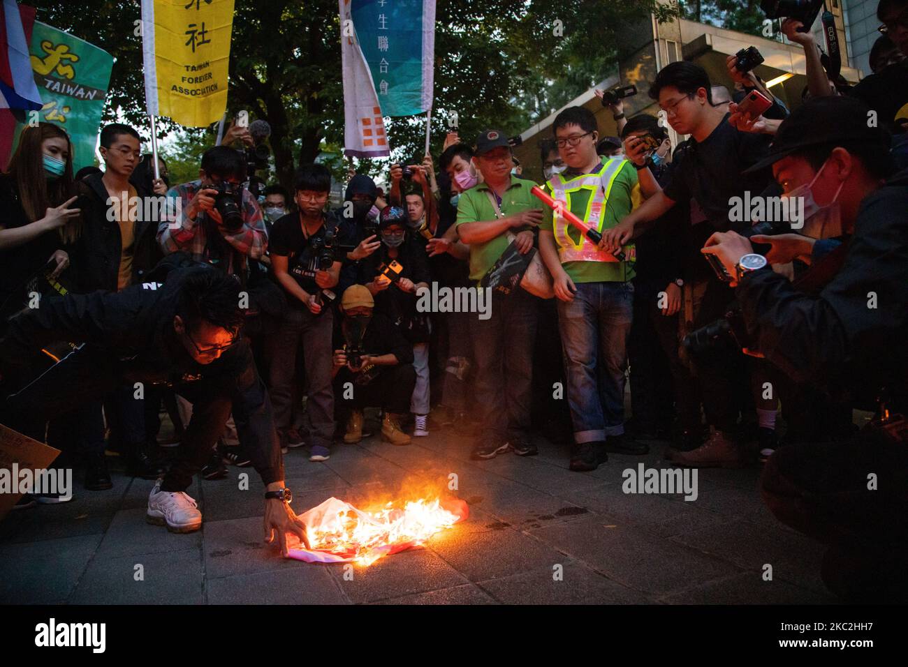 Die Demonstranten beobachten, wie die chinesische Flagge am 25. Oktober 2020 in Taipei, Taiwan, am Ende des marsches brennt. Hunderte marschierten am Sonntag in Taiwans Hauptstadt, um die Freilassung von 12 regierungsfeindlichen Demonstranten in Hongkong zu fordern, die angeblich illegal mit dem Boot nach Taiwan reisten, als die chinesischen Behörden sie im August festnahmen und festnahmen. (Foto von Annabelle Chih/NurPhoto) Stockfoto