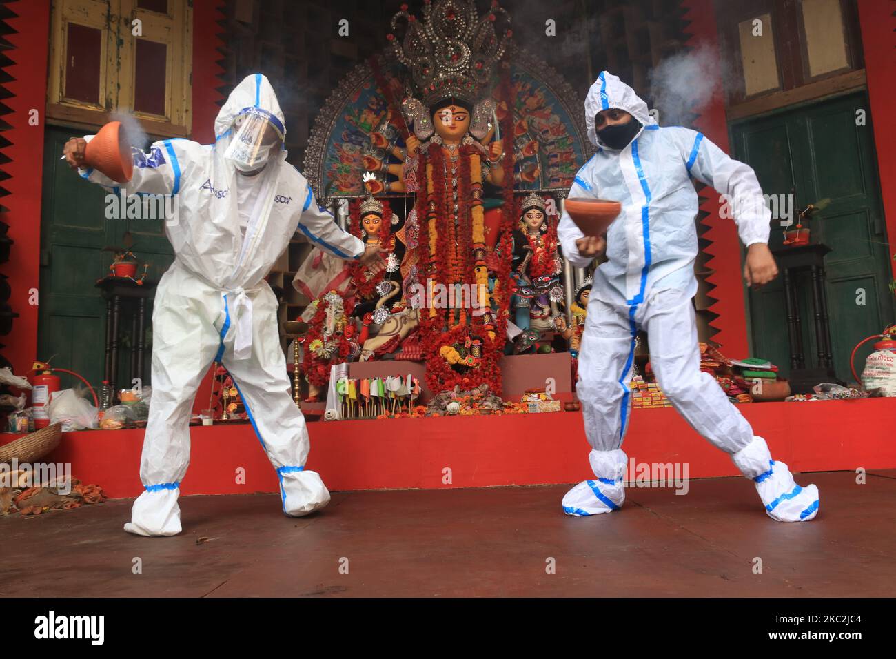 Hindu-Anhänger, die persönliche Schutzausrüstung tragen, führen Dhunuchi, einen traditionellen Tanz, am 25. Oktober 2020 vor einem Idol der Hindu-Göttin Durga während des Durga Puja Festivals in der Gemeinschaft Puja Pandal inmitten der COVID-19 Pandemie in Kalkutta, Indien, vor. (Foto von Debajyoti Chakraborty/NurPhoto) Stockfoto