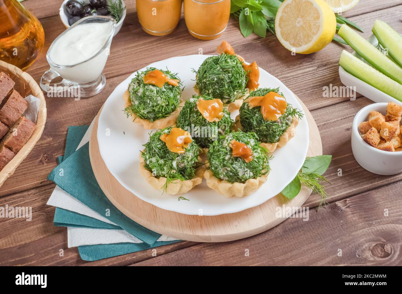 Tartlets, gefüllt mit Rindfleisch, Champignons und Kartoffeln mit Gemüse auf einem weißen Teller auf dunklem Holzboden. Stockfoto