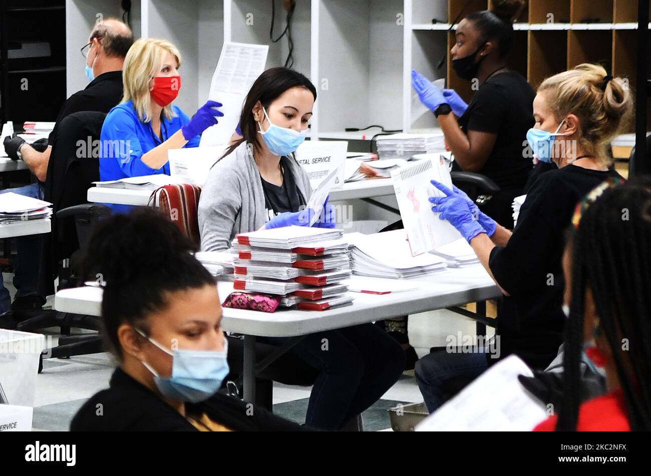 Mitarbeiter des Wahlbüros tragen Gesichtsmasken und Handschuhe, während sie am 26. Oktober 2020 im Wahlduplikationsraum des Wahlbüros von Orange County in Orlando, Florida, Briefwahlabstimmungen verarbeiten. Neun Tage vor den Wahlen vom 3. November haben bereits mehr Menschen in den diesjährigen Präsidentschaftswahlen ihre Stimme abgegeben, als im Rennen 2016 vorzeitig oder abwesend gewählt haben. (Foto von Paul Hennessy/NurPhoto) Stockfoto