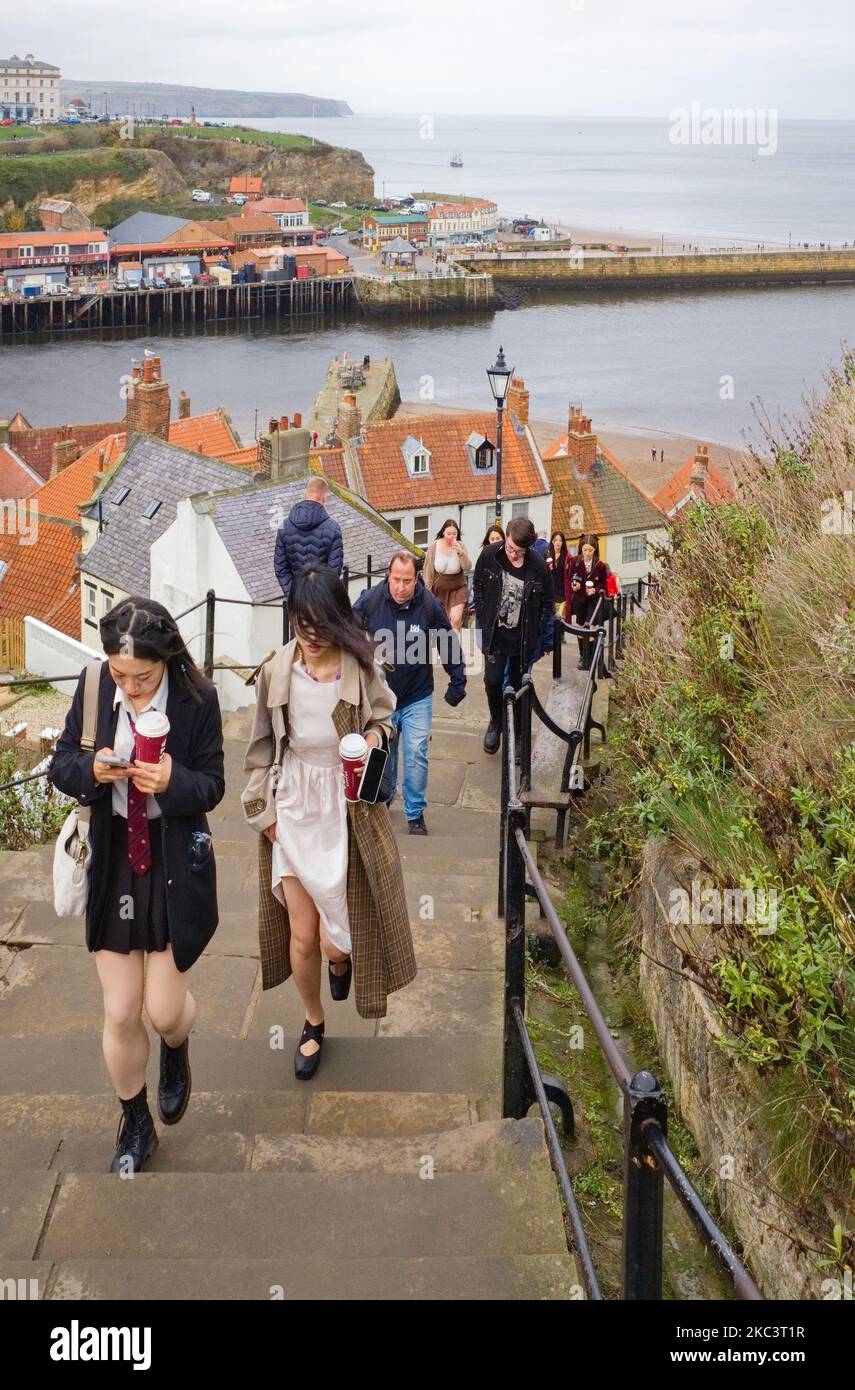 Die Leute gehen die 199 Stufen zur Kirche über dem Hafen von Whitby hinauf Stockfoto