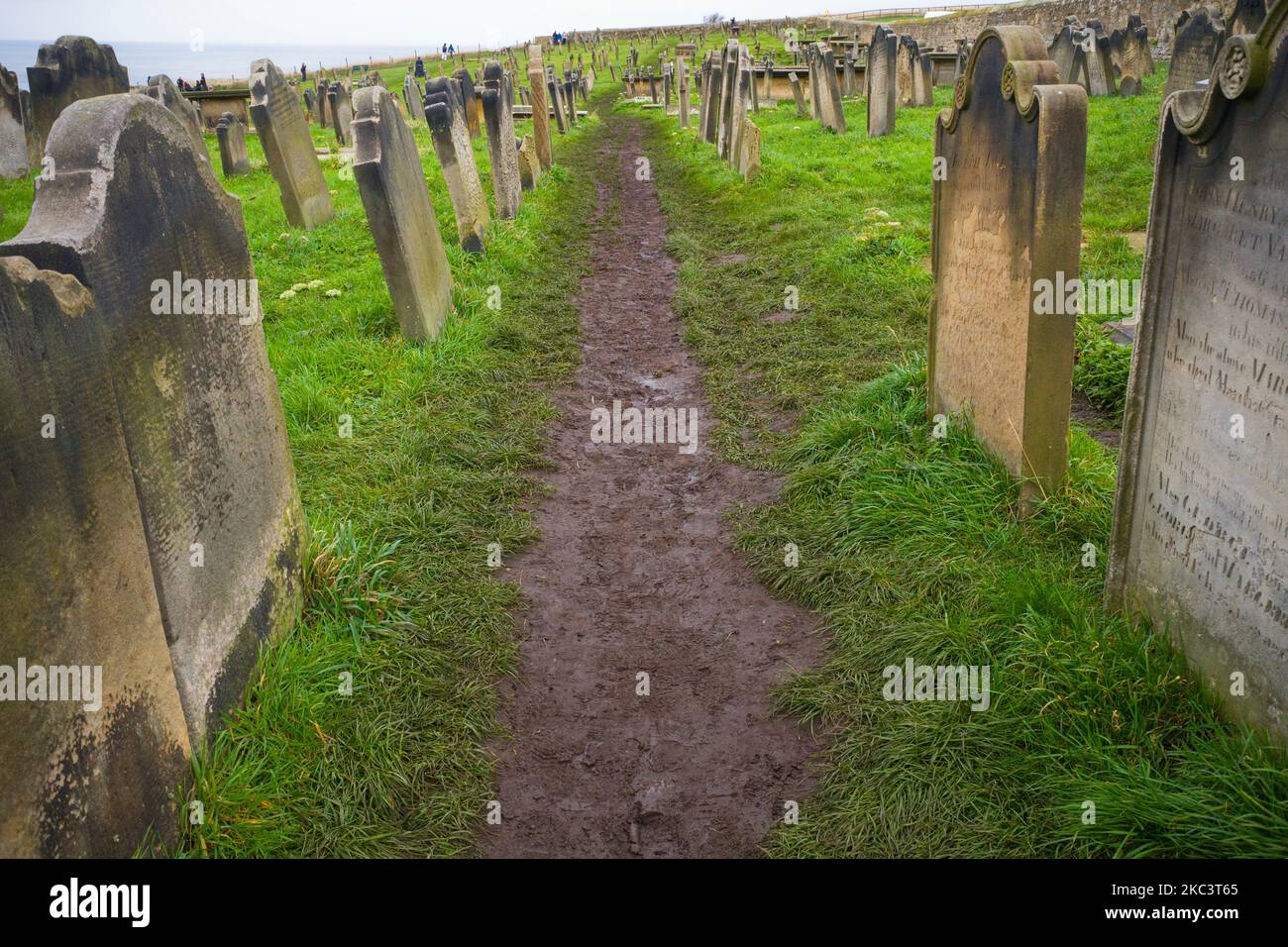 Schlammiger Fußweg zwischen den Grabsteinen in Whitby, North Yorkshire Stockfoto
