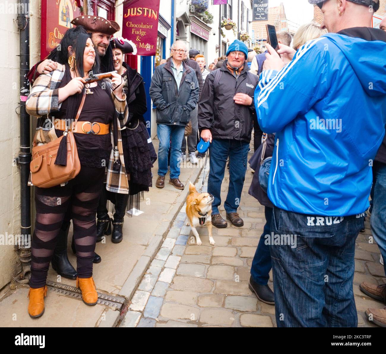 Ein älterer Mann sieht mit Überraschung zu einer Gruppe, die als Piraten verkleidet ist und während des Whitby-Gothy-Wochenendes fotografiert wird Stockfoto
