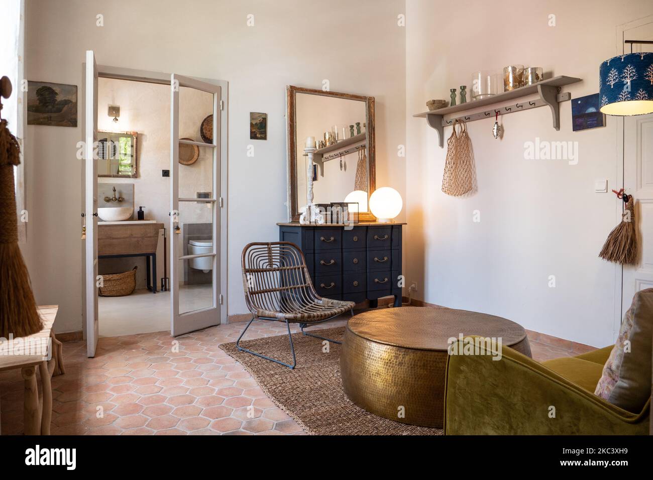 Ein kleiner Vintage-Raum mit einem Korbsessel, einer Bank, einem Vintage-Sessel und einem Backsteinboden Stockfoto