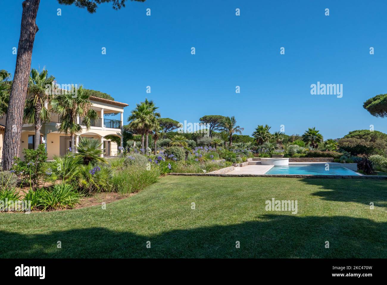 Das Äußere eines großen luxuriösen Gartens mit Palmen und einem Pool einer prächtigen weißen Villa Stockfoto