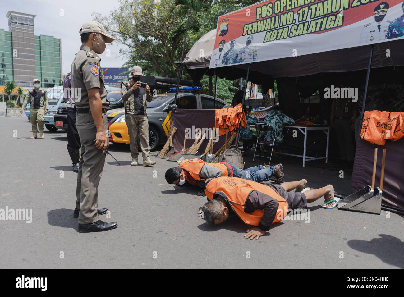 Sicherheitsbeamte beobachten, wie die Bewohner als Strafe dafür, dass sie keine Maske im öffentlichen Raum tragen, um Gesundheitsprotokolle in der Stadt Salatiga, Zentraljava, Indonesien, umzusetzen, hochgedrückt werden, 24. November 2020. (Foto von Galih Yoga/NurPhoto) Stockfoto