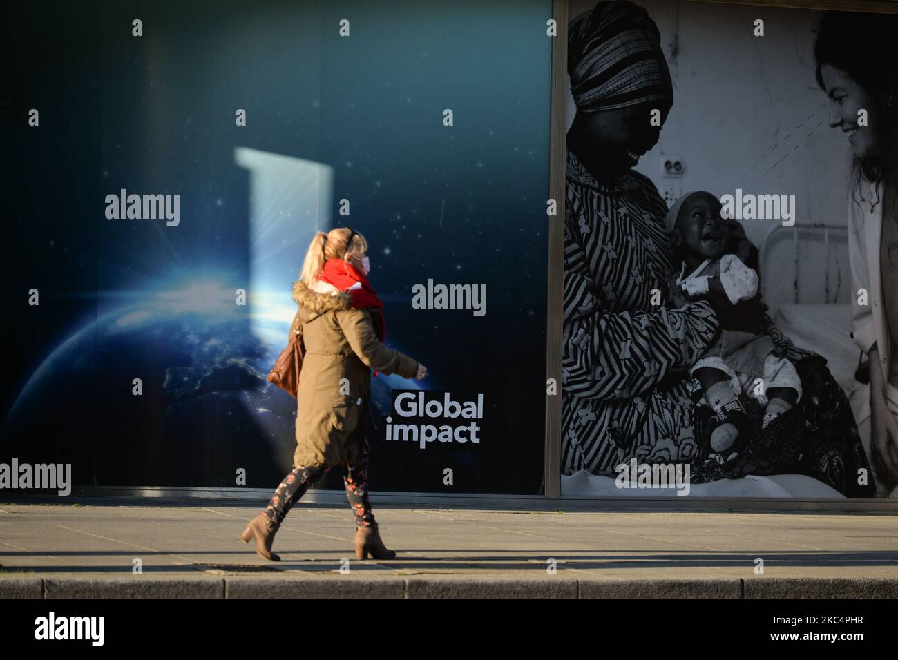 Eine Frau mit Gesichtsmaske kommt am Fenster „Global Impact“ im Stadtzentrum von Dublin vorbei. Am Freitag, den 27. November 2020, in Dublin, Irland. (Foto von Artur Widak/NurPhoto) Stockfoto
