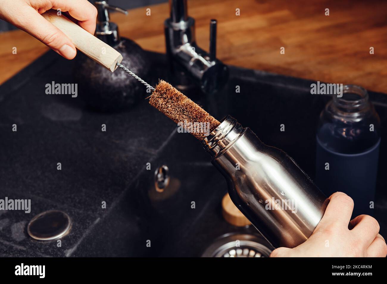 Waschen Reinigung wiederverwendbare Trinkflasche mit Kokosfaser-Fläschchenreinigungsbürste in der heimischen Küche. Nachhaltiges Lifestyle-Konzept. Stockfoto