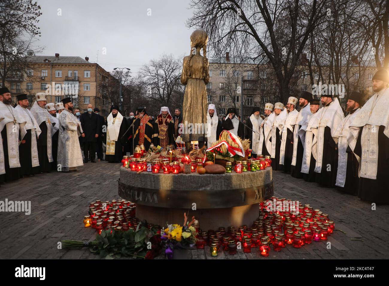 Priester verschiedener christlicher Konfessionen feiern einen Gedenkgottesdienst, während Menschen während der Trauerveranstaltung in Kiew, Ukraine, am 28. November Kerzen anzünden und Blumensträuße aus den Ohren und aus dem arrowwood zum Denkmal der großen Hungeropfer legen. 2020.die Ukraine ehrt das Gedenken an die Opfer der Hungersnöte und der Großen Hungersnot (Holodomor) von 1932 bis 1933, als 4,5 Millionen Ukrainer, darunter 600.000 ungeborene Kinder, vom sowjetischen Regime unter Joseph Stalin verhungert wurden. (Foto von Sergii Chartschenko/NurPhoto) Stockfoto