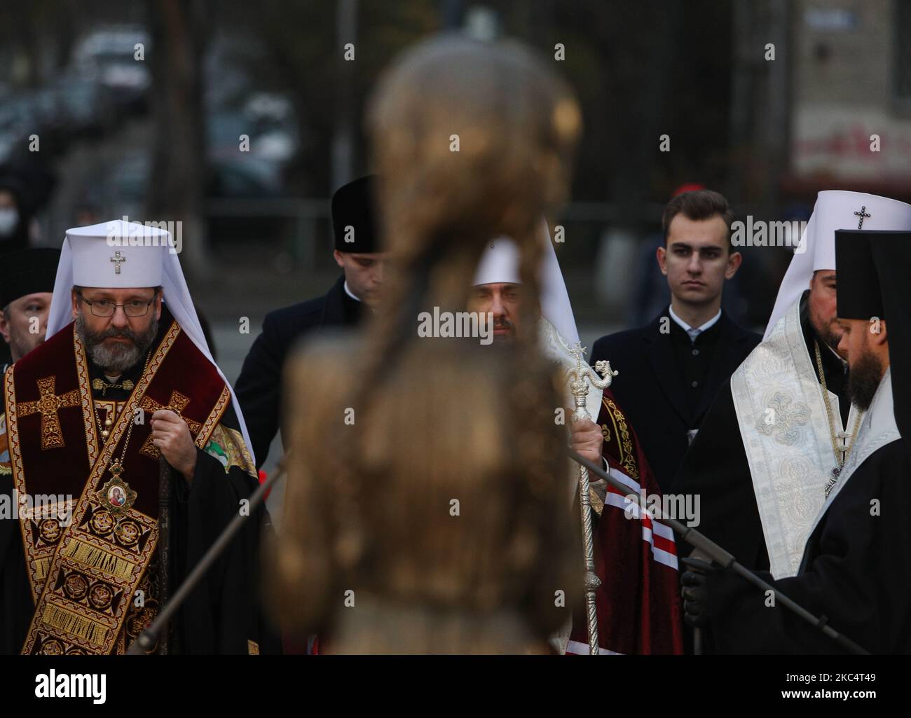 Priester verschiedener christlicher Konfessionen feiern einen Gedenkgottesdienst, während Menschen während der Trauerveranstaltung in Kiew, Ukraine, am 28. November Kerzen anzünden und Blumensträuße aus den Ohren und aus dem arrowwood zum Denkmal der großen Hungeropfer legen. 2020.die Ukraine ehrt das Gedenken an die Opfer der Hungersnöte und der Großen Hungersnot (Holodomor) von 1932 bis 1933, als 4,5 Millionen Ukrainer, darunter 600.000 ungeborene Kinder, vom sowjetischen Regime unter Joseph Stalin verhungert wurden. (Foto von Sergii Chartschenko/NurPhoto) Stockfoto