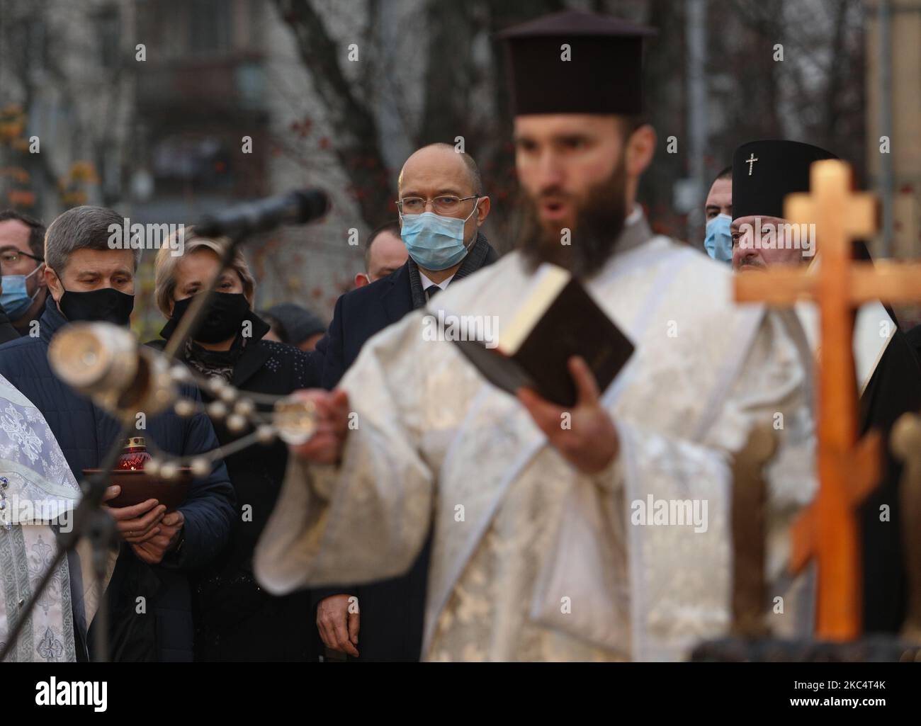 Priester verschiedener christlicher Konfessionen feiern einen Gedenkgottesdienst, während Menschen während der Trauerveranstaltung in Kiew, Ukraine, am 28. November Kerzen anzünden und Blumensträuße aus den Ohren und aus dem arrowwood zum Denkmal der großen Hungeropfer legen. 2020.die Ukraine ehrt das Gedenken an die Opfer der Hungersnöte und der Großen Hungersnot (Holodomor) von 1932 bis 1933, als 4,5 Millionen Ukrainer, darunter 600.000 ungeborene Kinder, vom sowjetischen Regime unter Joseph Stalin verhungert wurden. (Foto von Sergii Chartschenko/NurPhoto) Stockfoto