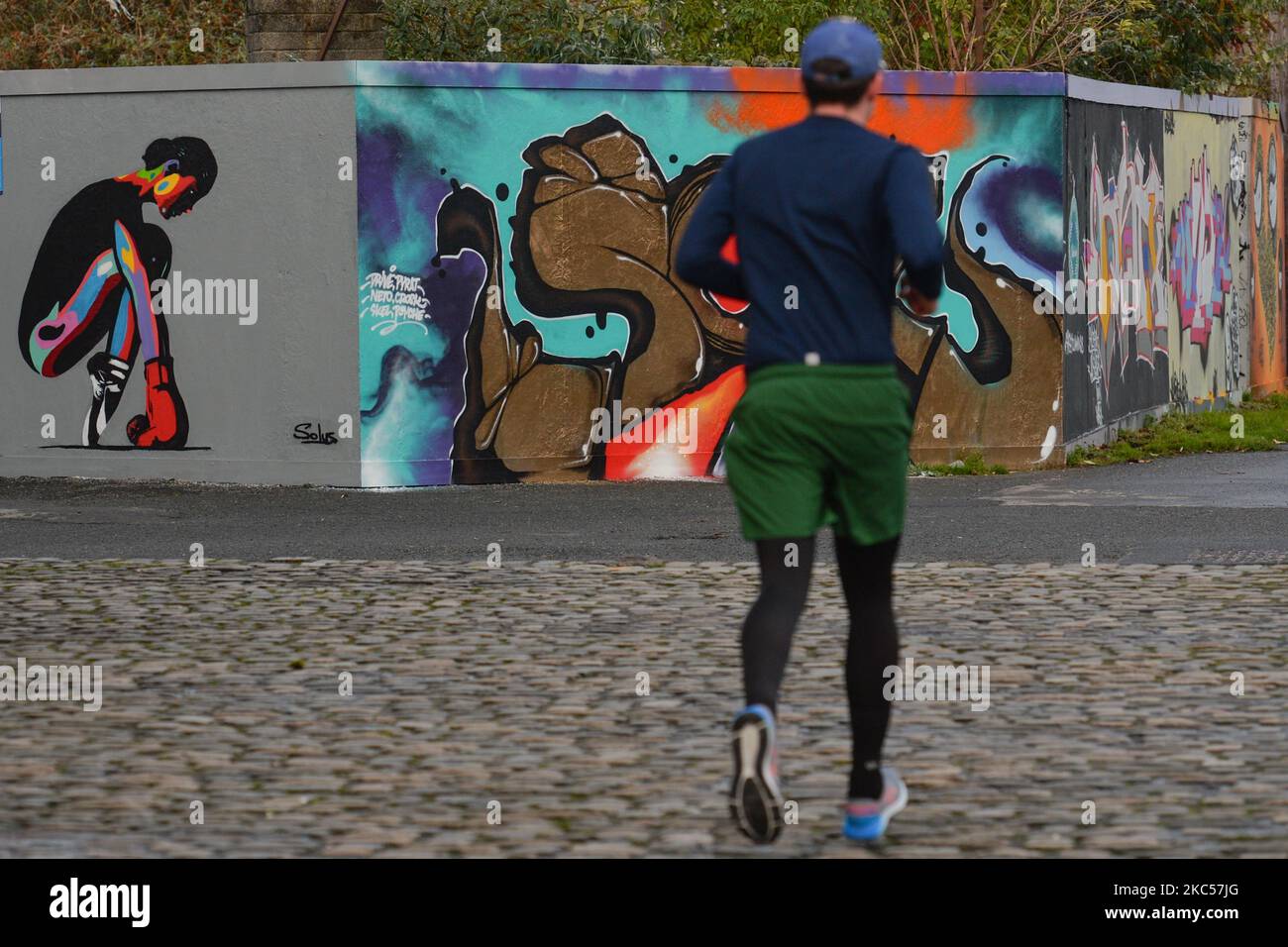 Ein Läufer, der an einer Wand mit Graffiti vorbeikommt, in Dublin. Am Donnerstag, den 3. Dezember 2020, in Dublin, Irland. (Foto von Artur Widak/NurPhoto) Stockfoto