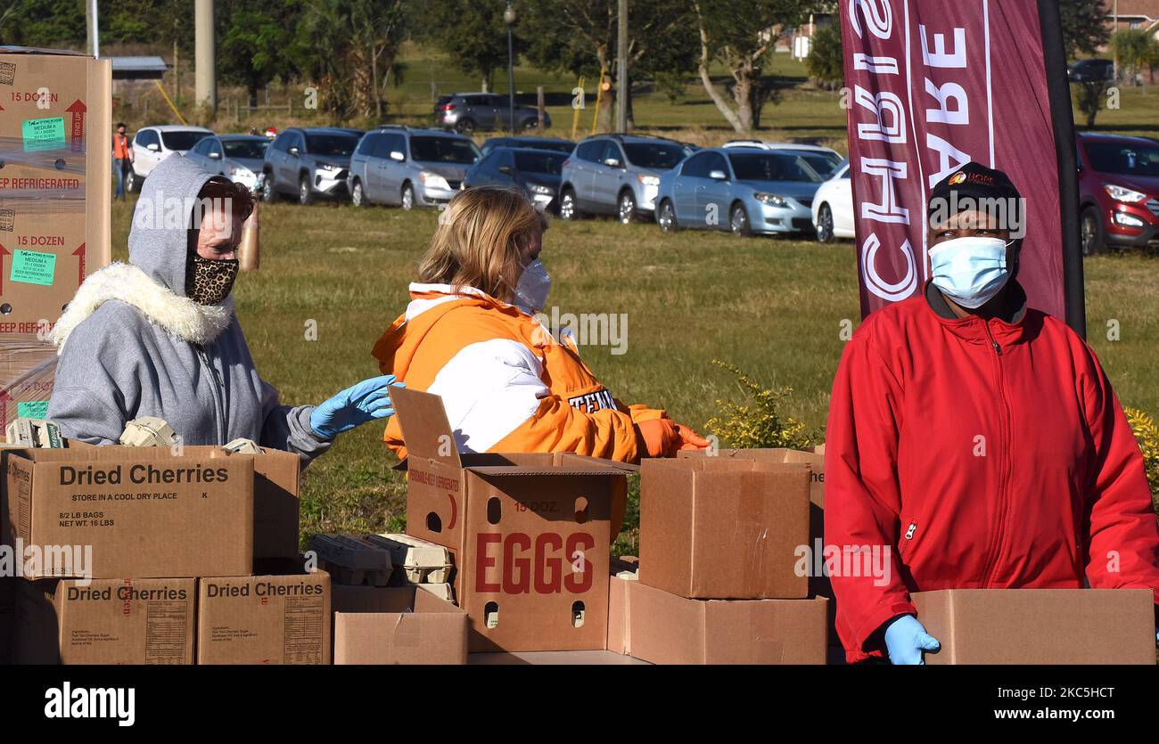 Freiwillige bereiten sich darauf vor, Kisten mit Nahrungsmittelhilfe in eine Reihe wartender Autos beim „Share your Christmas Food Distribution“-Event zu laden, das von der Second Harvest Food Bank of Central Florida, Faith Neighborhood Center, gesponsert wird. Und WESH 2 bei der Hope International Church am 9. Dezember 2020 in Groveland, Florida, bei Orlando. Die Lebensmittelbanken im Zentrum Floridas kämpfen darum, denjenigen zu helfen, die während der Weihnachtszeit unter der COVID-19-Pandemie mit Ernährungsunsicherheit konfrontiert sind. (Foto von Paul Hennessy/NurPhoto) Stockfoto