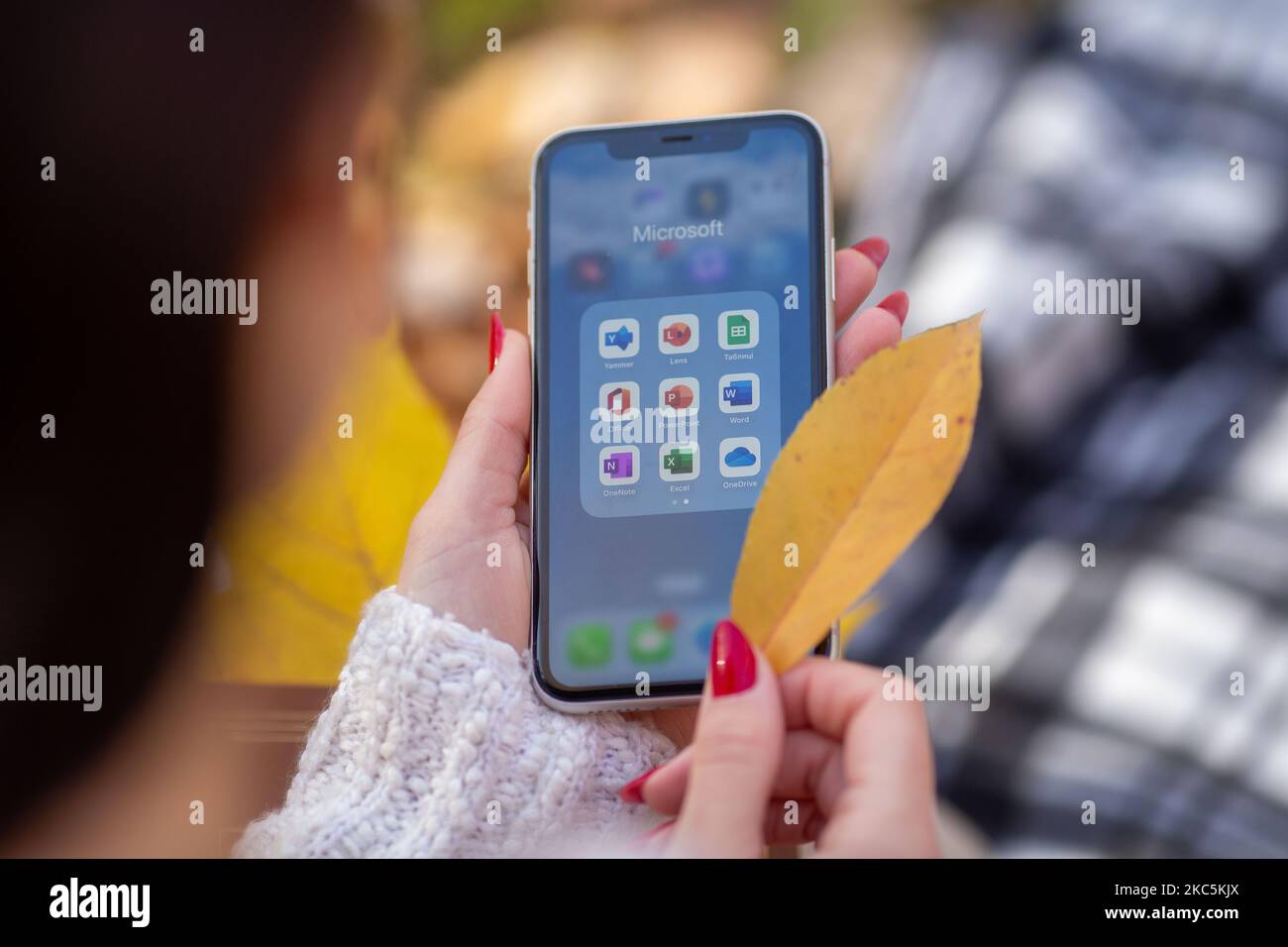 Kiew, Ukraine - 4. November 2022. Microsoft 365-Anwendungen sind auf einem iPhone sichtbar, das von einem Mädchen im Hintergrund gehalten wird - Office, Word, Excel, PowerPoi Stockfoto