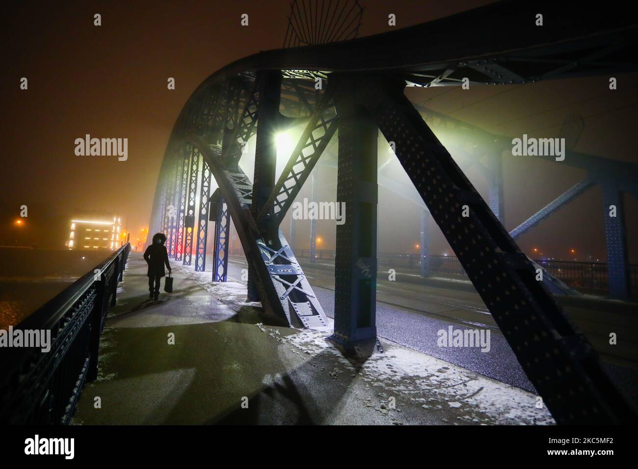 Eine Frau geht am 11. Dezember 2020 an einem nebligen Winterabend in Krakau, Polen, über eine Brücke. (Foto von Beata Zawrzel/NurPhoto) Stockfoto