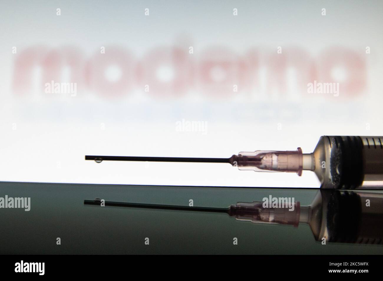 Foto-Illustration einer medizinischen Spritze mit einer Nadel vor dem Logo des Pharmakonzerns Moderna. Moderna erwartet die amerikanische Entscheidung, eine Zulassung für die Notfallverwendung, den Impfstoffkandidaten mRNA-1273 am 17 2020. Dezember von der FDA und die europäische Zulassung für den COVID-19-Impfstoff im Januar 2021. Moderna ist ein amerikanisches Biotechnologie-Unternehmen mit Sitz in Cambridge, Massachusetts, das Impfstofftechnologien auf Basis von Boten-RNA mRNA entwickelt. Die Coronavirus-Pandemie, eine der größten Gesundheitskrisen der Welt, wird zu dem größten Impfprogramm in der menschlichen Geschichte führen. Amste Stockfoto