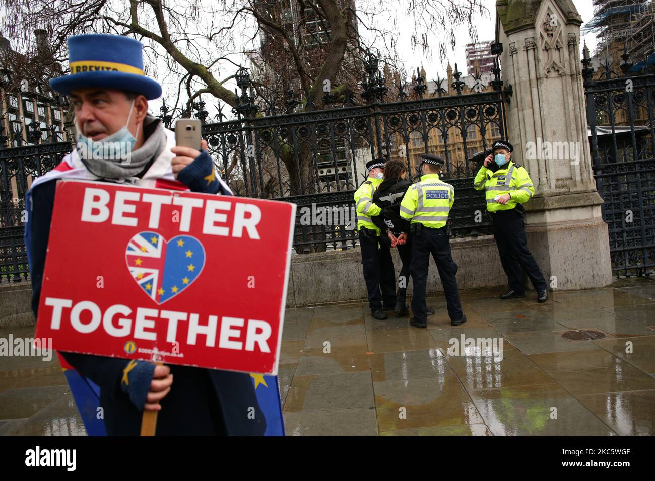 Der Anti-Brexit-Aktivist Steve Bray sieht zu, wie ein Aktivist, der gegen die Beschränkungen der Coronavirus-Sperre protestiert und alle vorgeschriebenen Covid-19-Impfungen am 14. Dezember 2020 auf dem Parliament Square in London, England, von Polizeibeamten verhaftet wird. Es wird erwartet, dass London unmittelbar unter die „Tier 3“-Beschränkungen gestellt wird, was auf einen „sehr hohen“ Coronavirus-Alarmlevel hinweist und dazu führt, dass Pubs, Bars, Cafés und Restaurants geschlossen werden müssen, außer dass sie einen Take-away- und Lieferservice anbieten. Die Stadt wurde am Ende der vierwöchigen, england-weiten Sperre am 2. Dezember, A, wieder zu den „hohen“ Beschränkungen der Stufe 2 zurückgebracht Stockfoto