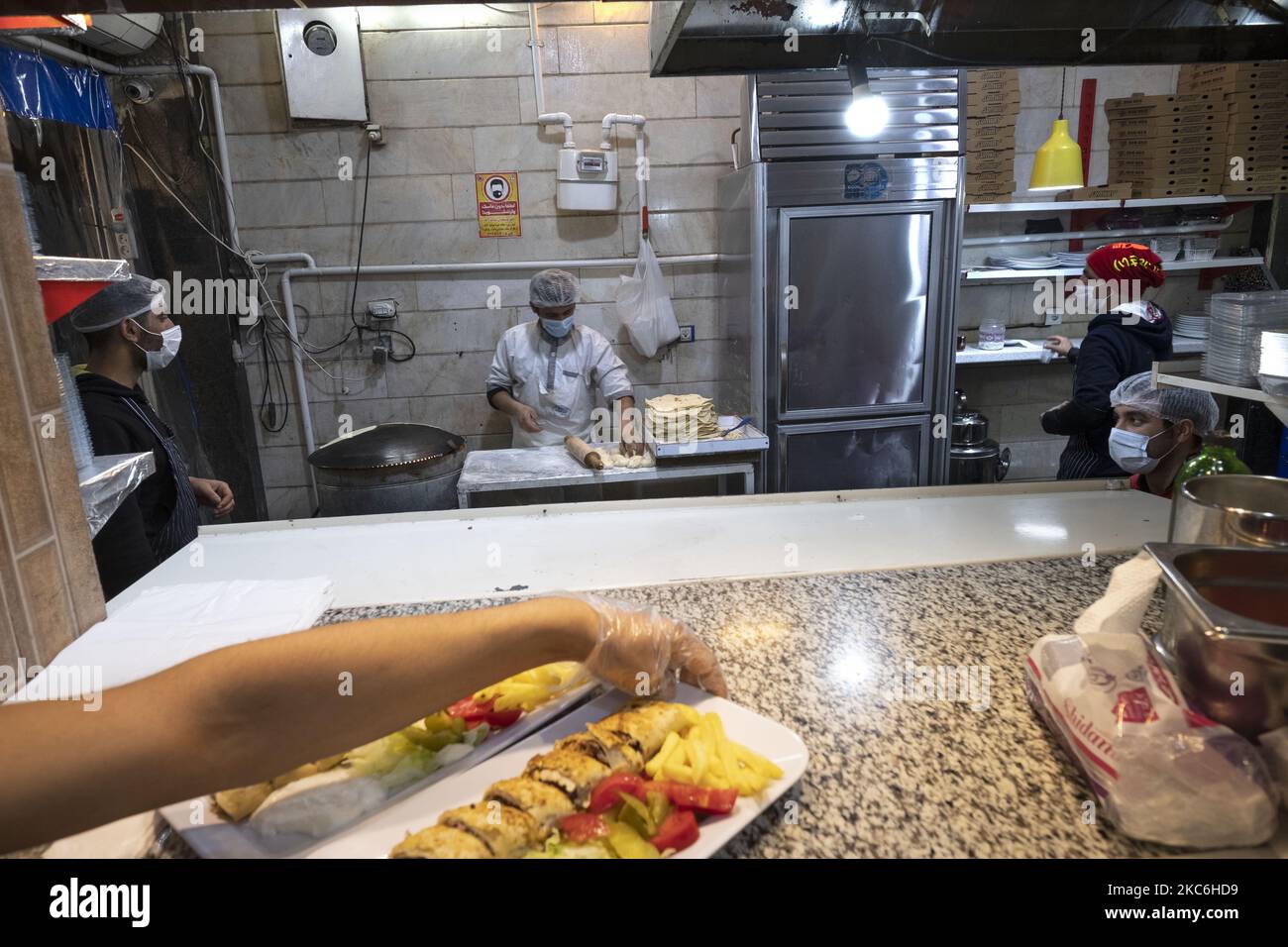 Irakische Arbeiter mit Schutzmasken arbeiten in einem arabischen Restaurant im Viertel Dolat-Abad, das inmitten des Ausbruchs der neuen Coronavirus-Krankheit (COVID-19) im Iran am 25. Dezember 2020 ein Hauptwohngebiet für irakische Einwanderer und ihre Familien im Süden Teherans ist. MORTEZA NIKOUBAZL/NurPhoto (Foto von Morteza Nikoubazl/NurPhoto) Stockfoto