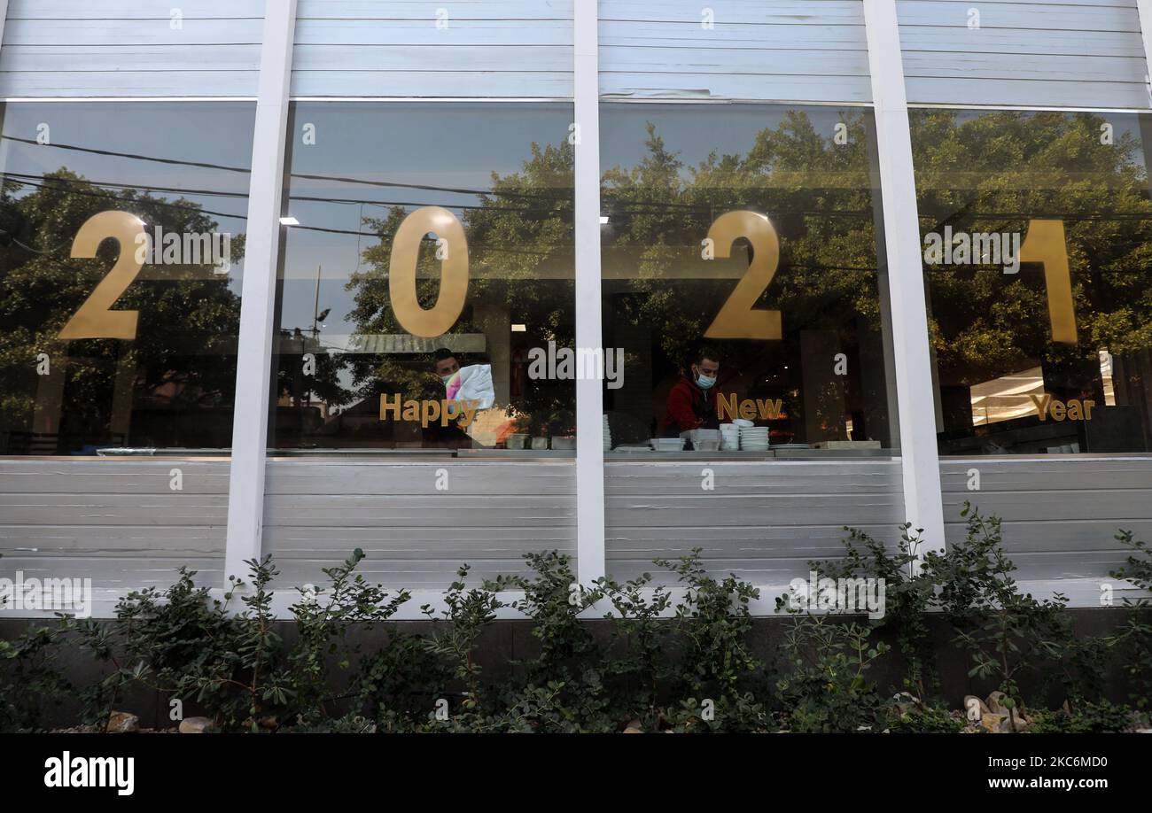 Palästinensische Arbeiter werden vor dem neuen Jahr in Gaza-Stadt am 30. Dezember 2020 in einem mit Licht des Jahres 2021 geschmückten Restaurant gesehen. (Foto von Majdi Fathi/NurPhoto) Stockfoto
