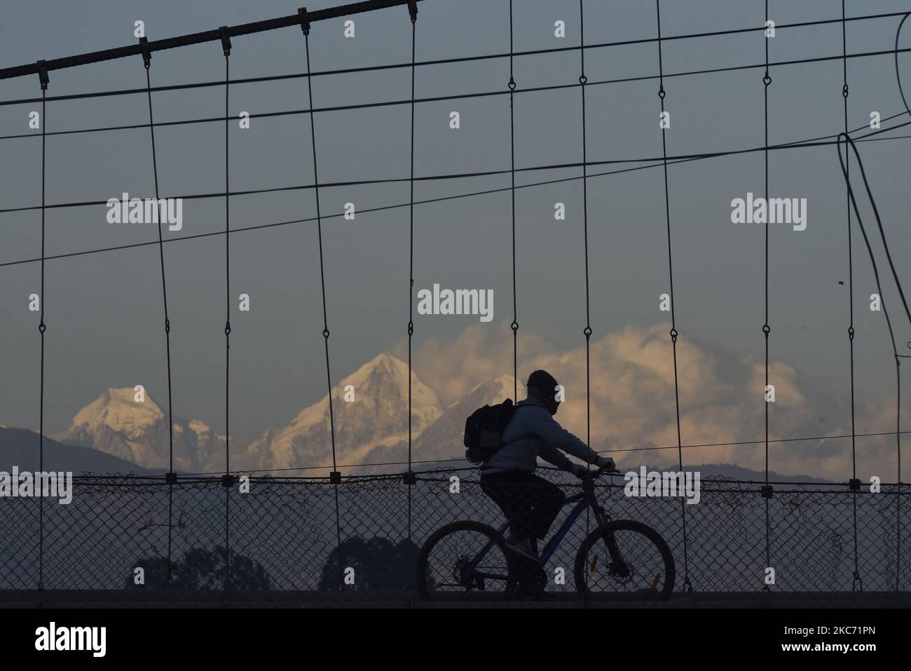 Ein Radsportler, der die Hängebrücke als Mount Dorje Lakhpa überquerte, sah am Mittwoch, den 06. Januar 2021, im Hintergrund nach zwei Tagen gefährlicher Luftverschmutzung in Kathmandu, Nepal. Der AQI-Verschmutzungsgrad stieg am Montag stetig auf den gefährlichen Stand bei 606 AQI um 11:00 Uhr und am Mittwoch bei 220 AQI um 11:00 Uhr. (Foto von Narayan Maharjan/NurPhoto) Stockfoto