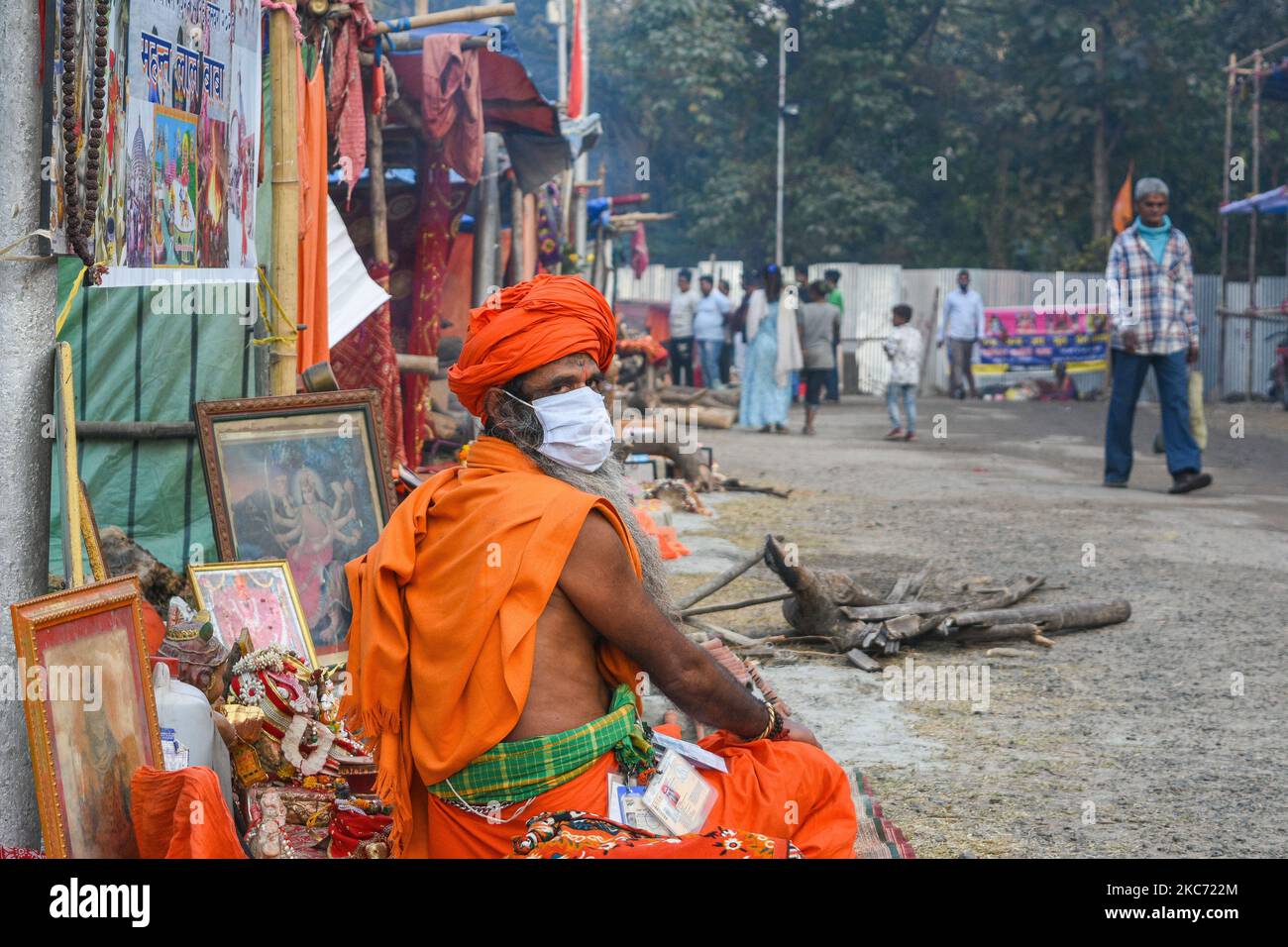 Ein heiliger, der eine Schutzmaske im Transit-Lagergelände von Gangsagar in Kalkata trägt. Gangasagar Messe ist die zweitgrößte Begräbnung der Hindu-Pilger nach Kumbh mela. Die Gangasagar-Mela wird jährlich auf der Insel Sagar beobachtet.jedes Jahr während Makar Sankranti besuchen eifrige Anhänger aus dem ganzen Land die insel sagar, um ein heiliges Bad im Zusammenfluss von Ganges und der Bucht von Bengalen zu nehmen und dann am Kapil Muni Ashram auf der Insel anzubeten. Der Tempel wird unter den Anhängern hoch verehrt.Dieses Jahr wird die Messe eingeschränkt und unter strengen COVID-Protokollen der Regierung wird die übliche Menge woul Stockfoto