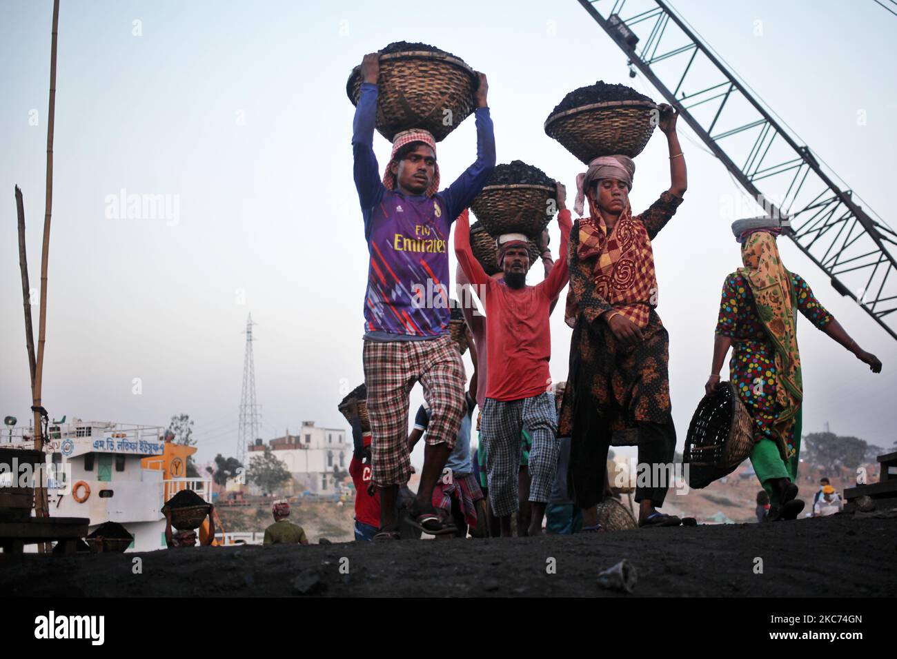 Arbeiter tragen Kohle auf Körben, als sie diese am Freitag, den 08. Januar 2021, von einem Frachtschiff am Ufer des Flusses Buriganga in Dhaka, Bangladesch, entladen. Der derzeitige Verbrauch von Kohle für die Stromerzeugung liegt bei etwa 3,5 Millionen Tonnen pro Jahr für die beiden Kohlekraftwerke in Bangladesch, eines in Barapukuria (440MW) in Dinajpur und das andere in der neu in Betrieb genommenen Payra-Anlage (660MW) in Patuakhali. Nach dem Medienbericht würde der Kohleverbrauch für die Stromerzeugung im Jahr 2030 bei der Umsetzung des Masterplans 2016 10-mal höher und im Jahr 2041 20-mal höher sein als die PR Stockfoto