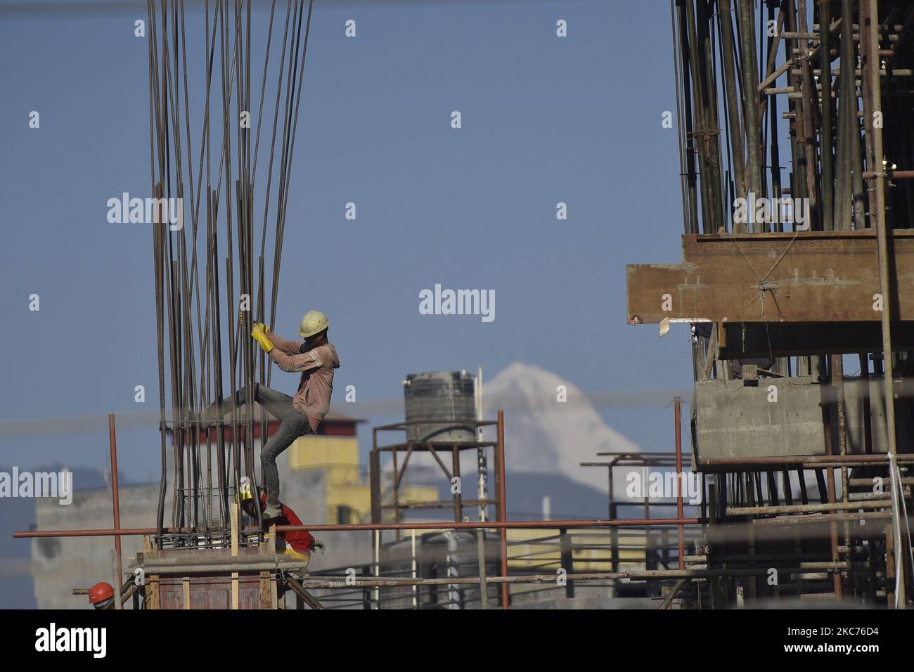 Arbeiter, die am Bau eines neuen Gebäudes als Berge im Hintergrund in Kathmandu, Nepal, am Freitag, 8. Januar 2021 arbeiten. (Foto von Narayan Maharjan/NurPhoto) Stockfoto