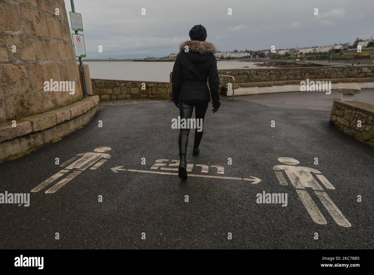 Eine Frau kommt an einem sozialen Distanzierungsschild 2m in der Nähe des Strandes von Seapoint in Dublin vorbei, während die Covid-19-Sperre auf Level 5 abgeschlossen wird. Irland hat die höchste Covid-19-Infektionsrate der Welt, nachdem in der vergangenen Woche mehr als 45.700 Fälle im Bundesstaat verzeichnet wurden. Heute Abend meldete das Gesundheitsministerium 4.929 neue Covid-19-Fälle und 8 Todesfälle für die Republik Irland. Eine Rekordzahl von 1.582 Covid-19 Patienten war im Krankenhaus. Die Zahl der Intensivpflegebedürftigen ist um 21 auf 146 Personen höher. Am Montag, den 11. Januar 2021, in Dublin, Irland. (Foto von Artur Widak/NurPhoto) Stockfoto