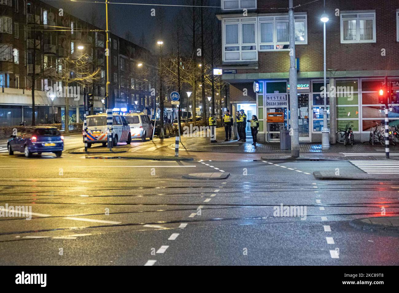 Polizeibeamte und Fahrzeuge, die in Amsterdam eingesetzt wurden, um die Ausgangssperre zu überblicken. Verlassene Straßen der niederländischen Stadt Amsterdam und die Polizei, die die Menschen auf ordnungsgemäße Dokumentation überprüft und Geldstrafen von 95euro feststellt, nach der Nachtruhe und einem Aufruf zum Protest. Der vierte Tag mit der Ausgangssperre im Land ist nach Protesten und Zusammenstößen in den Vortagen ruhiger geworden. Die Sperrstunde wurde zur Bekämpfung der Ausbreitung des Virus verhängt, nachdem die Sperrmaßnahmen zur Bekämpfung des Anstiegs des Coronavirus Covid-19 und der neuen Mutation der Pandemie ergriffen wurden. Die erste Sperrstunde nach dem Zweiten Weltkrieg wurde verhängt. Restrik Stockfoto