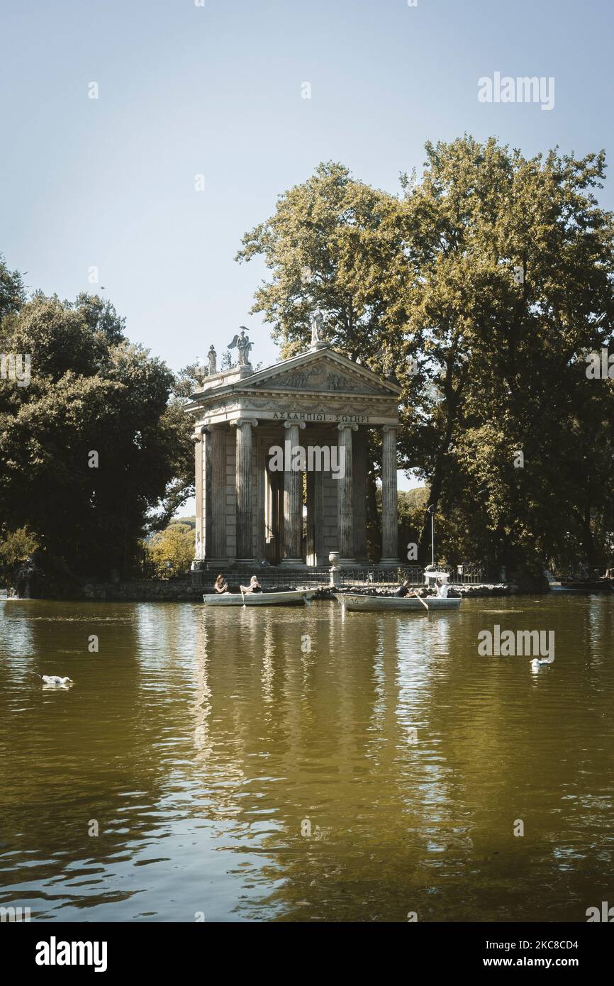 Eine Vertikale des Tempels des Aesculapius vor dem See der Villa Borghese und seinen Besuchern, die umhersegeln, Rom, Italien Stockfoto