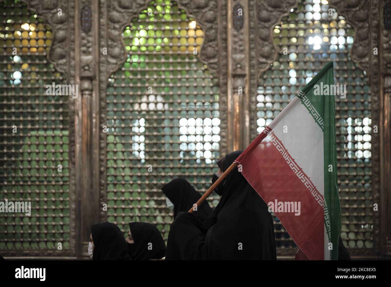 Eine verschleierte iranische Frau, die eine Schutzmaske trägt, hält eine iranische Flagge, während sie am ersten Tag des Sieges des Jahrestages der Islamischen Revolution auf dem Friedhof Behesht-e Zahra im Süden Teherans inmitten des COVID-19 vor dem Grab des verstorbenen iranischen Führers Ayatollah Ruhollah Khomeini steht Ausbruch im Iran am 31. Januar 2021. Der Iran feiert zehn Tage nach dem heutigen Tag den 42.. Jahrestag des Sieges der Islamischen Revolution, aber der Ausbruch der neuen Coronavirus-Krankheit (COVID-19) hat die diesjährigen Feierlichkeiten nicht wie in den vergangenen Jahren gefeiert. (Foto von Morteza Nikoubazl/NurPhoto) Stockfoto