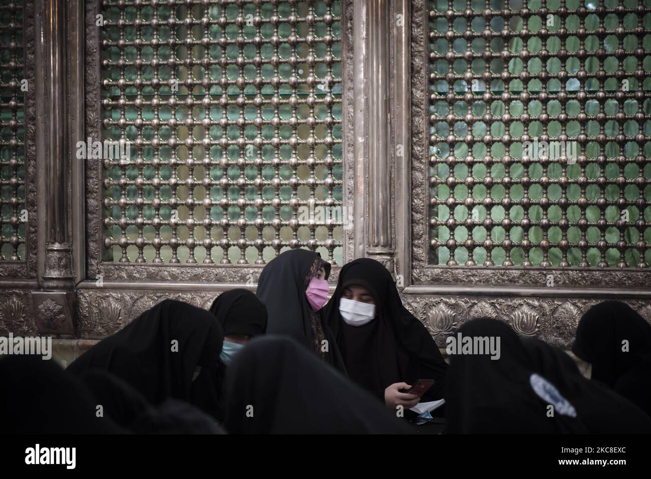 Zwei verschleierte iranische Frauen mit Schutzmaske sprechen miteinander, während sie am ersten Tag des Sieges des Jahrestages der Islamischen Revolution auf dem Friedhof Behesht-e Zahra im Süden Teherans inmitten des Ausbruchs der COVID-19 neben dem Grab des verstorbenen iranischen Führers Ayatollah Ruhollah Khomeini sitzen Im Iran am 31. Januar 2021. Der Iran feiert zehn Tage nach dem heutigen Tag den 42.. Jahrestag des Sieges der Islamischen Revolution, aber der Ausbruch der neuen Coronavirus-Krankheit (COVID-19) hat die diesjährigen Feierlichkeiten nicht wie in den vergangenen Jahren gefeiert. (Foto von Morteza Nikoubazl/NurPhoto) Stockfoto