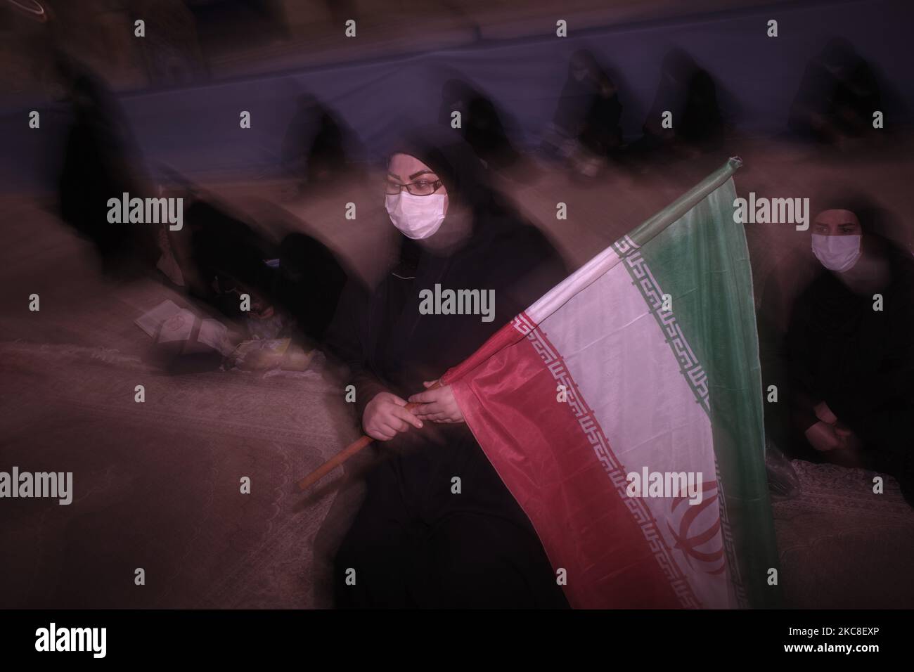 Eine verschleierte iranische Frau mit einer schützenden Gesichtsmaske hält eine iranische Flagge, während sie am ersten Tag des Sieges des Jahrestages der Islamischen Revolution auf dem Friedhof Behesht-e Zahra im Süden Teherans inmitten des Ausbruchs der COVID-19 im Heiligtum des verstorbenen iranischen Führers Ayatollah Ruhollah Khomeini sitzt Im Iran am 31. Januar 2021. Der Iran feiert zehn Tage nach dem heutigen Tag den 42.. Jahrestag des Sieges der Islamischen Revolution, aber der Ausbruch der neuen Coronavirus-Krankheit (COVID-19) hat die diesjährigen Feierlichkeiten nicht wie in den vergangenen Jahren gefeiert. (Foto von Morteza Nikoubazl/NurPhoto) Stockfoto