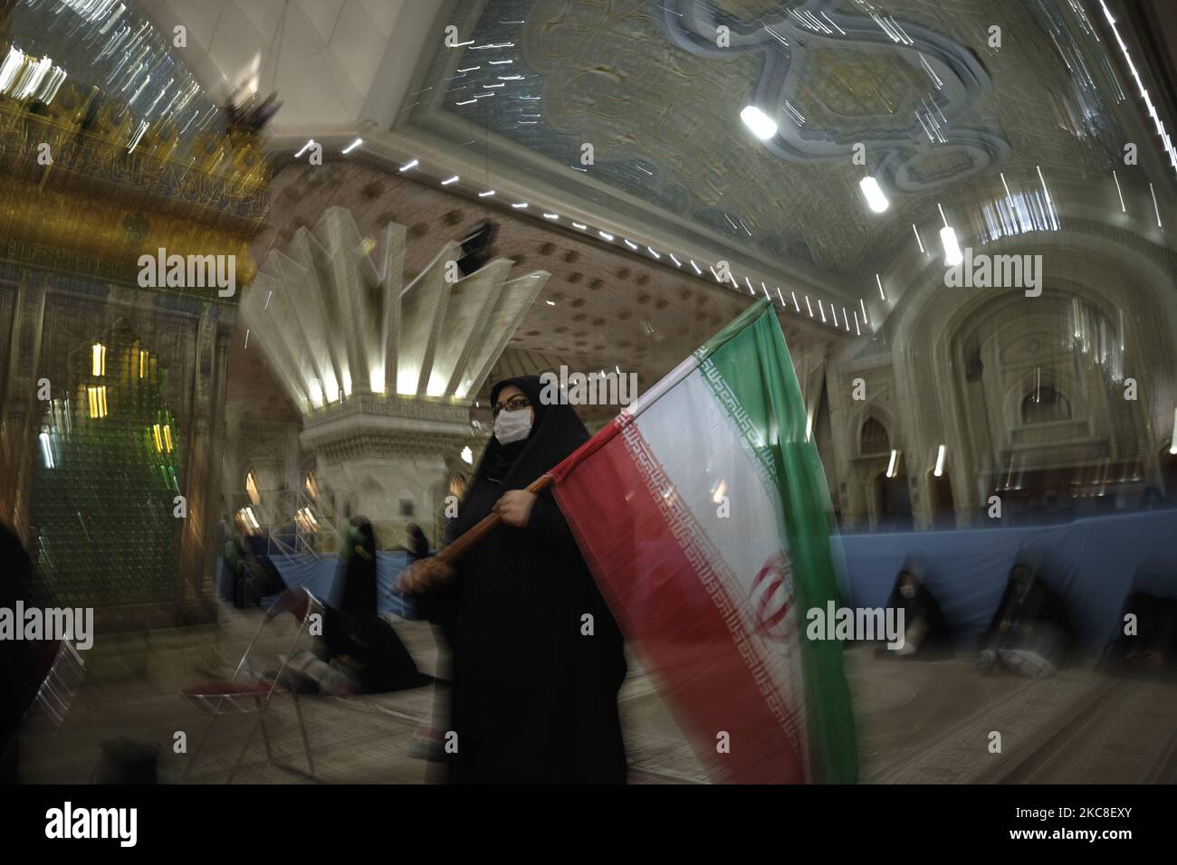 Eine verschleierte iranische Frau mit einer schützenden Gesichtsmaske hält eine iranische Flagge, während sie am ersten Tag des Sieges des Jahrestages der Islamischen Revolution auf dem Friedhof Behesht-e Zahra im Süden Teherans inmitten des Ausbruchs der COVID-19 im Heiligtum des verstorbenen iranischen Führers Ayatollah Ruhollah Khomeini steht Im Iran am 31. Januar 2021. Der Iran feiert zehn Tage nach dem heutigen Tag den 42.. Jahrestag des Sieges der Islamischen Revolution, aber der Ausbruch der neuen Coronavirus-Krankheit (COVID-19) hat die diesjährigen Feierlichkeiten nicht wie in den vergangenen Jahren gefeiert. (Foto von Morteza Nikoubazl/NurPhoto) Stockfoto