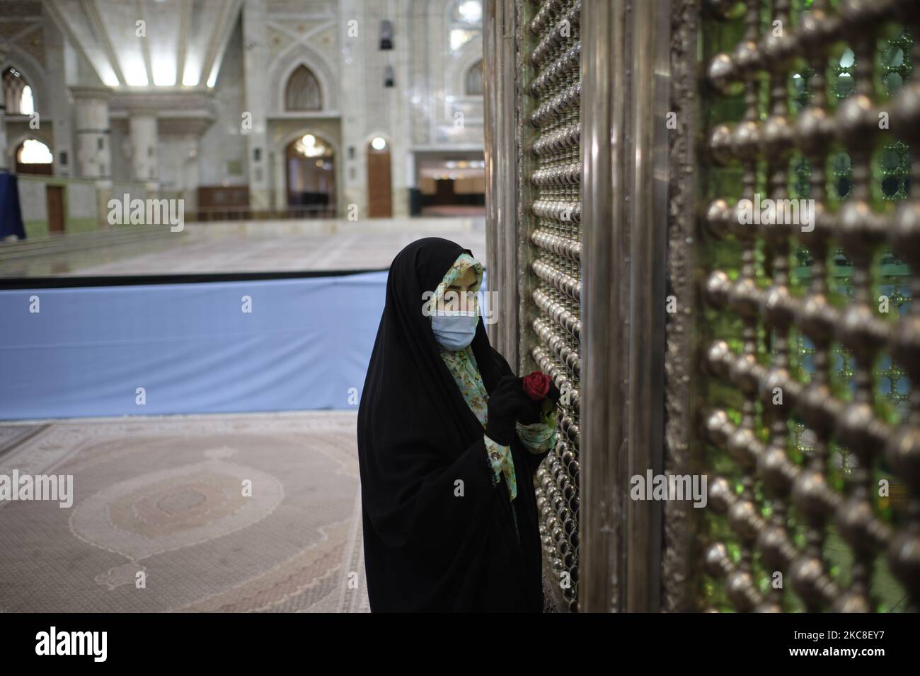 Eine verschleierte iranische Frau, die eine schützende Gesichtsmaske trägt, hält beim Gebet eine Blume fest, während sie neben dem Grab des verstorbenen iranischen Führers Ayatollah Ruhollah Khomeini am ersten Tag des Sieges des Jahrestages der Islamischen Revolution auf dem Friedhof Behesht-e Zahra im Süden Teherans inmitten des steht COVID-19 Ausbruch im Iran am 31. Januar 2021. Der Iran feiert zehn Tage nach dem heutigen Tag den 42.. Jahrestag des Sieges der Islamischen Revolution, aber der Ausbruch der neuen Coronavirus-Krankheit (COVID-19) hat die diesjährigen Feierlichkeiten nicht wie in den vergangenen Jahren gefeiert. (Foto von Morteza Nikoubazl/NurPhoto Stockfoto