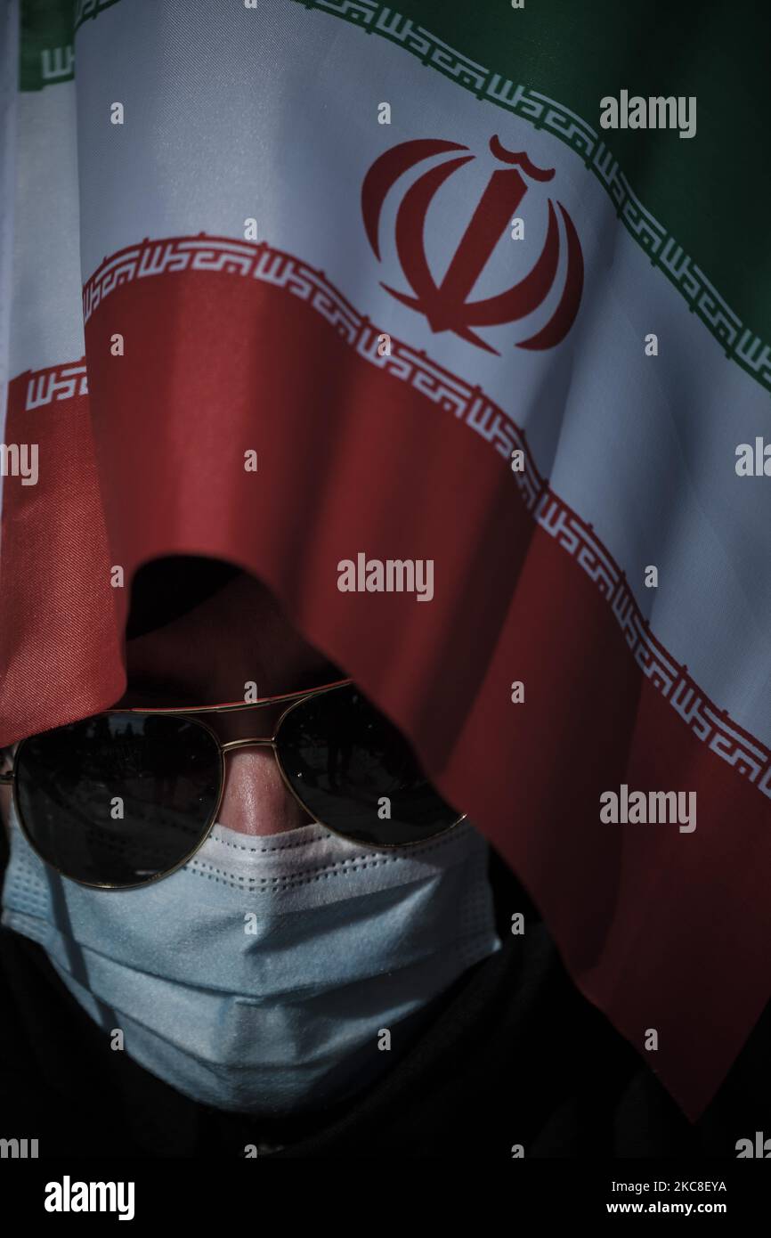 Eine verschleierte iranische Frau mit einer schützenden Gesichtsmaske hält eine iranische Flagge, als sie am ersten Tag der zehntägigen Feier anlässlich des Jahrestages des Sieges der Islamischen Revolution auf dem Behesht-e Zahra Friedhof im Süden Teherans inmitten des COVID-19-Ausbruchs im Iran am 31. Januar teilnimmt. 2021. Der Iran feiert zehn Tage nach dem heutigen Tag den 42.. Jahrestag des Sieges der Islamischen Revolution, aber der Ausbruch der neuen Coronavirus-Krankheit (COVID-19) hat die diesjährigen Feierlichkeiten nicht wie in den vergangenen Jahren gefeiert. (Foto von Morteza Nikoubazl/NurPhoto) Stockfoto