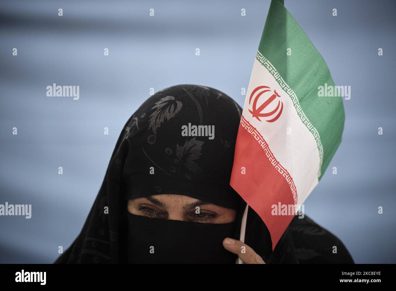 Eine verschleierte iranische Frau mit einer schützenden Gesichtsmaske hält eine iranische Flagge, während sie am ersten Tag des Sieges des Jahrestages der Islamischen Revolution auf dem Friedhof Behesht-e Zahra im Süden Teherans inmitten des Ausbruchs der COVID-19 im Heiligtum des verstorbenen iranischen Führers Ayatollah Ruhollah Khomeini sitzt Im Iran am 31. Januar 2021. Der Iran feiert zehn Tage nach dem heutigen Tag den 42.. Jahrestag des Sieges der Islamischen Revolution, aber der Ausbruch der neuen Coronavirus-Krankheit (COVID-19) hat die diesjährigen Feierlichkeiten nicht wie in den vergangenen Jahren gefeiert. (Foto von Morteza Nikoubazl/NurPhoto) Stockfoto