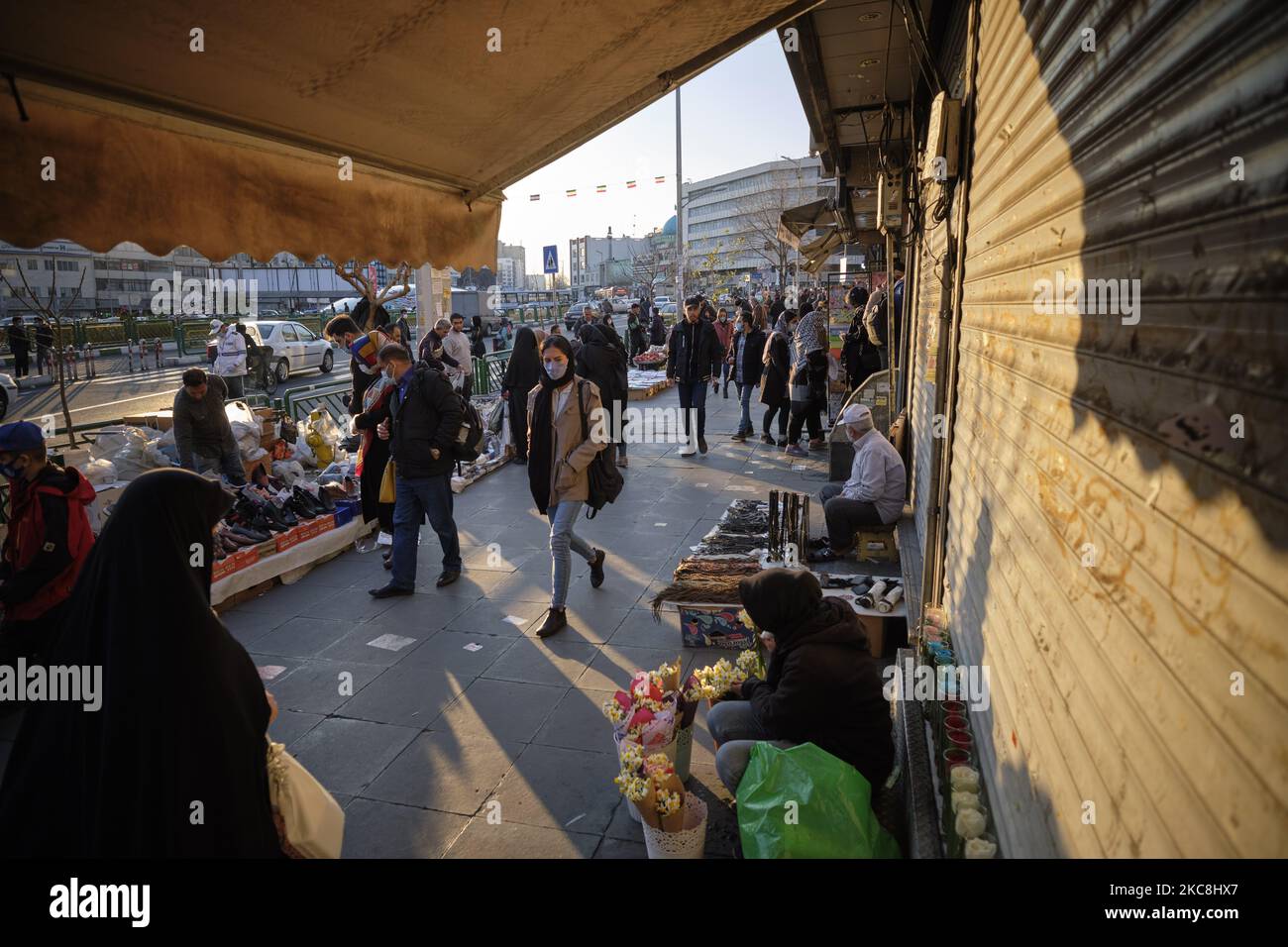 Iranische Menschen mit schützenden Gesichtsmasken gehen am 1. Februar 2021 an Händlern in der Enghelab (Revolution) Avenue im Zentrum von Teheran vorbei, während sie zehntägige Feierlichkeiten zum 42. Jahrestag des Sieges der iranischen Islamischen Revolution feiern. (Foto von Morteza Nikoubazl/NurPhoto) Stockfoto