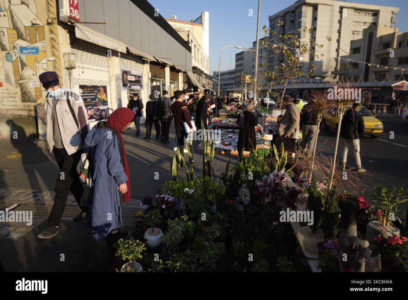 Iranische Menschen mit schützenden Gesichtsmasken gehen am 1. Februar 2021 an Händlern in der Enghelab (Revolution) Avenue im Zentrum von Teheran vorbei, während sie zehntägige Feierlichkeiten zum 42. Jahrestag des Sieges der iranischen Islamischen Revolution feiern. (Foto von Morteza Nikoubazl/NurPhoto) Stockfoto