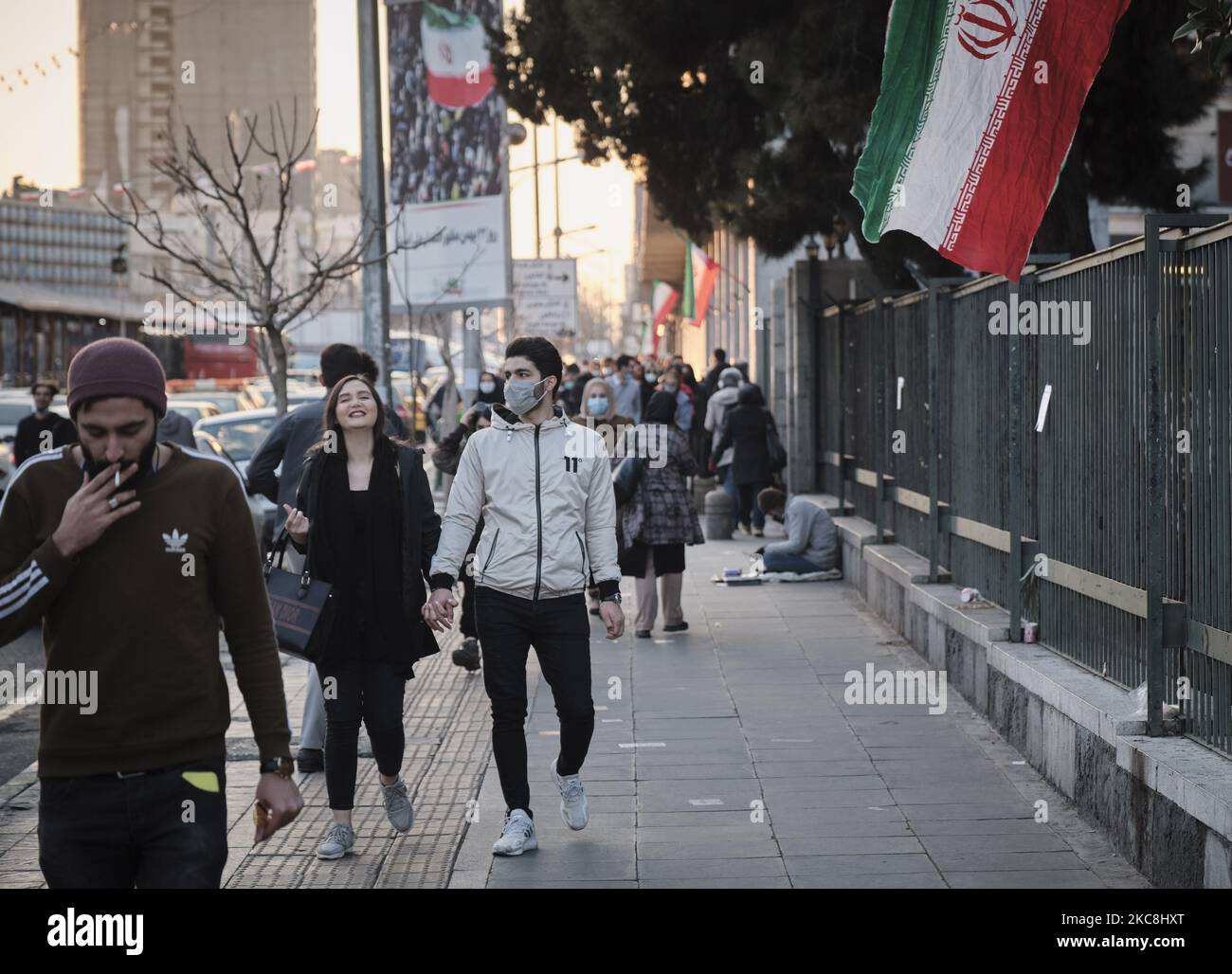 Ein iranisches Paar läuft am 1. Februar 2021 in der Enghelab (Revolution) Avenue entlang einer Straße, während zehn Tage lang im Zentrum von Teheran zum 42. Jahrestag des Sieges der Islamischen Revolution des Iran gefeiert wird. (Foto von Morteza Nikoubazl/NurPhoto) Stockfoto