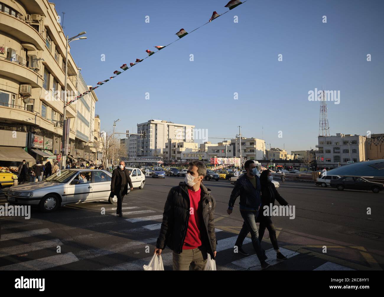 Iranische Menschen mit Schutzmaske überqueren am 1. Februar 2021 eine Allee auf dem Enghelab-Platz (Revolution) im Zentrum von Teheran, während zehntägige Feierlichkeiten zum 42. Jahrestag des Sieges der Islamischen Revolution im Iran stattfinden. (Foto von Morteza Nikoubazl/NurPhoto) Stockfoto