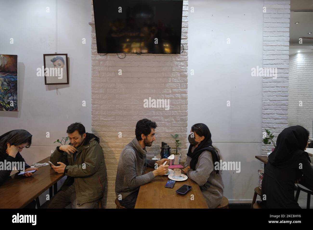 Iranische Jugendliche sitzen in einem Café in der Enghelab (Revolution) Avenue im Zentrum von Teheran während der zehntägigen Feierlichkeiten zum 42. Jahrestag des Sieges der Islamischen Revolution im Iran am 1. Februar 2021. (Foto von Morteza Nikoubazl/NurPhoto) Stockfoto
