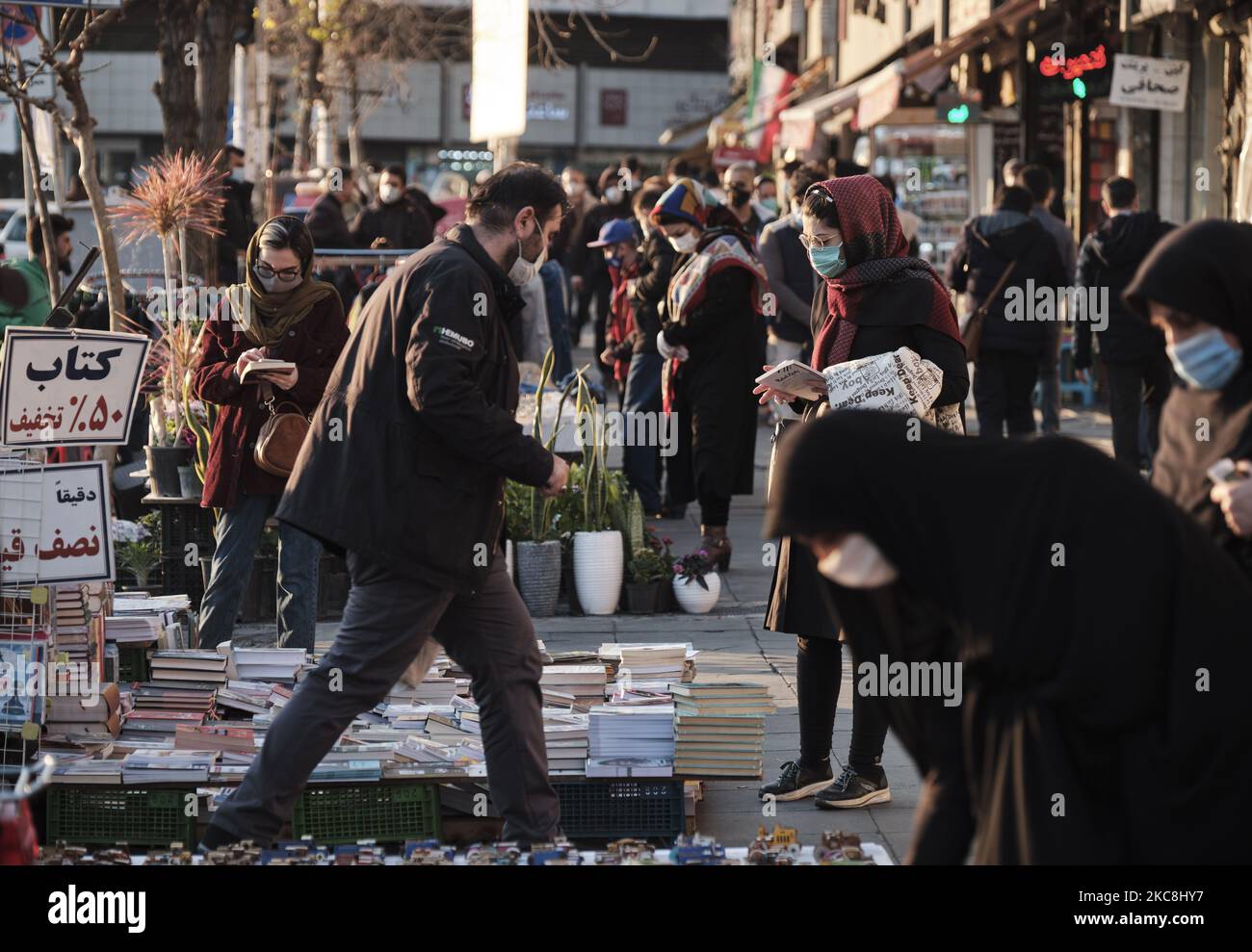 Iranische Frauen, die Schutzmasken tragen, kaufen bei Händlern auf dem Enghelab-Platz (Revolution) im Zentrum von Teheran während der zehntägigen Feierlichkeiten zum 42. Jahrestag des Sieges der Islamischen Revolution im Iran am 1. Februar 2021. (Foto von Morteza Nikoubazl/NurPhoto) Stockfoto