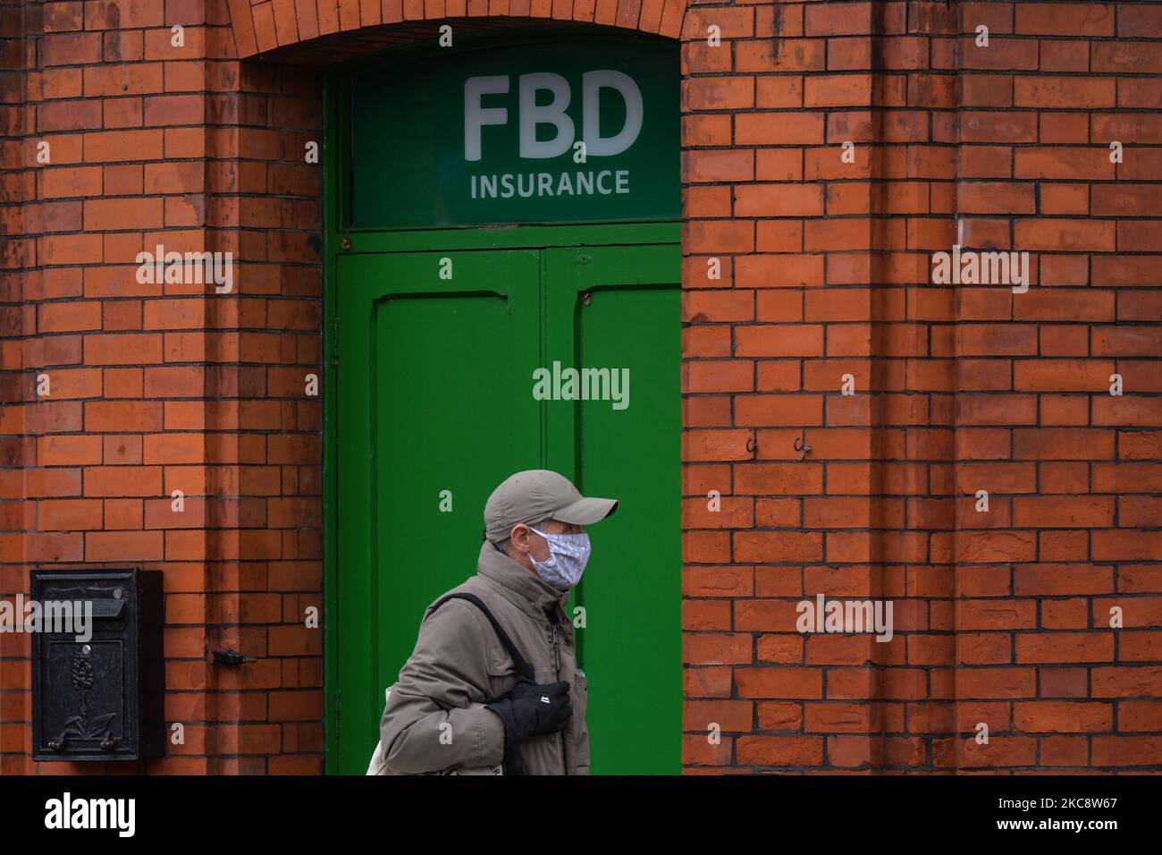 Ein Mann mit Gesichtsmaske, der während der Covid-19-Sperre auf Ebene 5 an einer FBD-Versicherungsabteilung im Stadtzentrum von Dublin vorbei läuft. Der High Court hat entschieden, dass drei Dublin Pubs und eines von Athlone berechtigt sind, von der FBD Insurance für die Störung ihrer Geschäfte aufgrund der Covid-19-Pandemie entschädigt zu werden. Am Samstag, den 6. Februar 2021, in Dublin, Irland. (Foto von Artur Widak/NurPhoto) Stockfoto