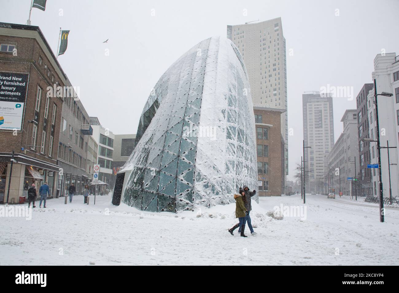 Schnee rund um De Blob, ein berühmtes Wahrzeichen in Eindhoven mit Menschen in der Nähe. Blizzard vom Schneesturm Darcy in den Niederlanden, dem ersten starken Schneefall mit starken Winden nach 2010, der den Transport im ganzen Land störte. Die Niederländer erwachten am Sonntag mit einer Schneeschicht, die alles bedeckte. Viele Unfälle ereigneten sich auf den Straßen aufgrund des Sturms und der eisigen Bedingungen, während es auch Probleme mit den Zügen gab. In der Stadt Eindhoven in Nordbrabant wurde der Bahn- und Busverkehr eingestellt, der Flughafen folgte und der Luftverkehr umgeleitet. In der CI gingen Leute nach draußen Stockfoto