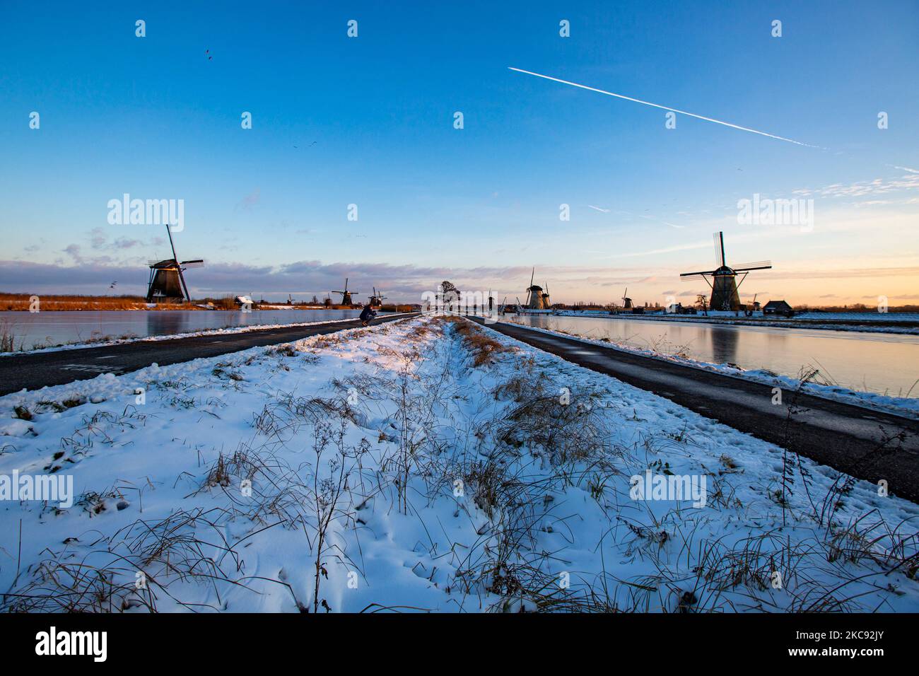 Zauberhaftes Gestrüppel rund um die Sonnenuntergangszeit und Dämmerung mit klarem Winterhimmel an den gefrorenen Kanälen und Windmühlen von Kinderdijk in den Niederlanden. Das Land ist mit arktischem Wetter, schweren niedrigen Temperaturen, Schneefall und starken Winden aufgrund des Sturms Darcy konfrontiert, der Probleme beim Transport und im täglichen Leben verursachte. Viele der Kanäle wurden eisgefroren, da die Temperatur unter Null liegt, da das kalte Wetter manchmal -16C erreicht, während das Land von Schnee bedeckt ist. Kinderdijk und die Windmühlen im Polder Alblasserwaard, ist eine berühmte Attraktion, ein holländisches Wahrzeichen und ein UNESCO-Weltkulturerbe, Attraktin Stockfoto