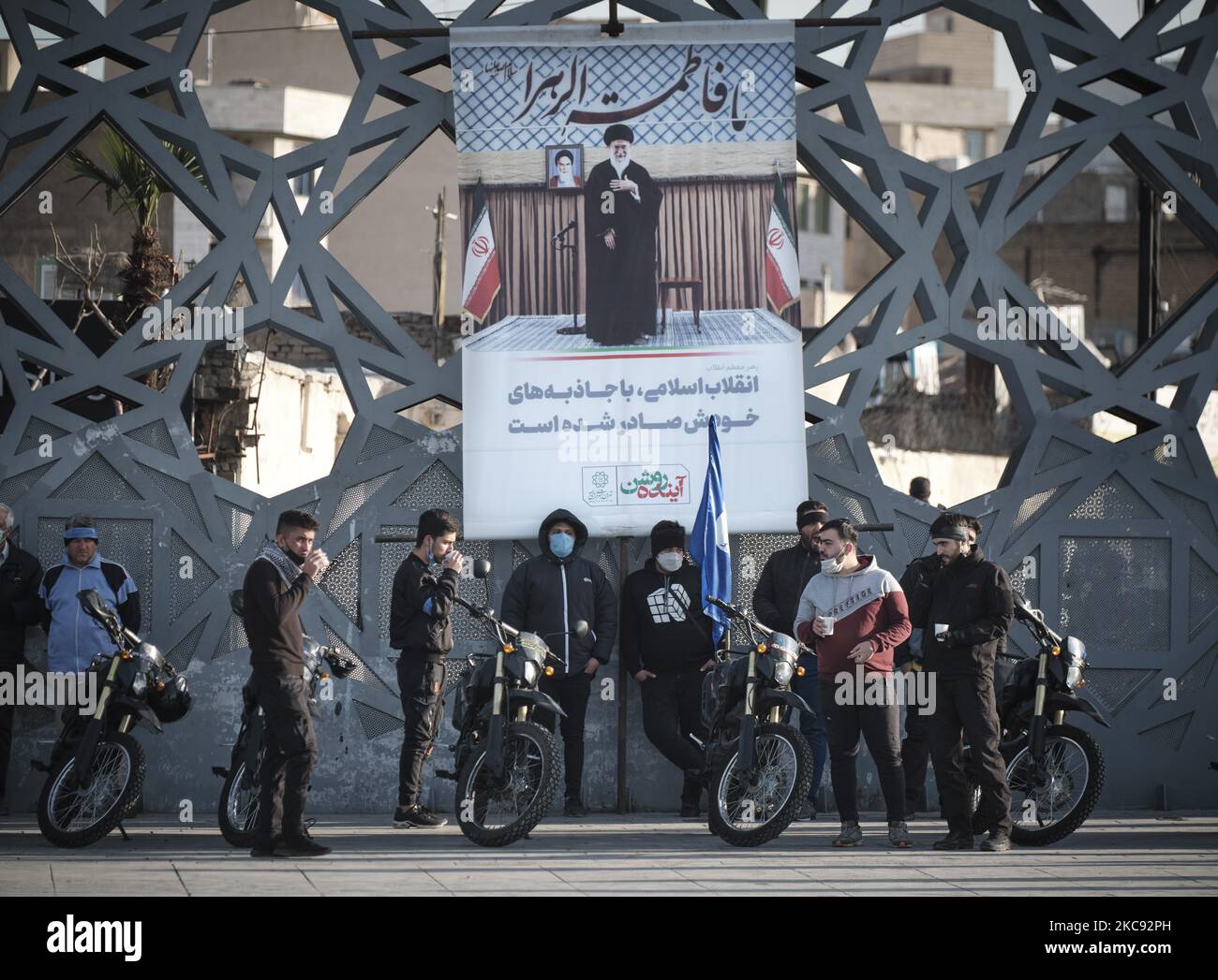 Iranische Männer stehen neben ihren Motorrädern unter einem Porträt des iranischen Obersten Führers Ayatollah Ali Khamenei, während sie an einer Kundgebung zum Gedenken an den 42.. Jahrestag des Sieges der Islamischen Revolution teilnehmen. Das fand am 10. Februar 2021 auf dem Imam Hussein-Platz im Süden Teherans mit Motorrädern statt, als die neue Coronavirus-Krankheit (COVID-19) im Iran ausbrach. (Foto von Morteza Nikoubazl/NurPhoto) Stockfoto
