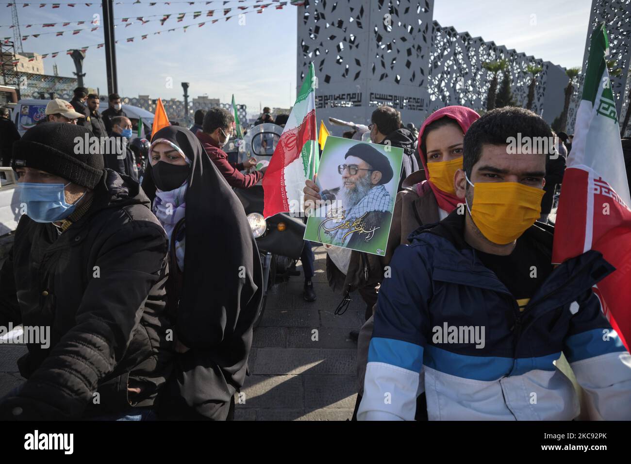 Eine iranische Frau, die eine schützende Gesichtsmaske trägt, hält ein Porträt des iranischen Obersten Führers Ayatollah Ali Khamenei, während sie an einer Kundgebung zum Gedenken an den 42.. Jahrestag des Sieges der Islamischen Revolution teilnimmt. Das fand am 10. Februar 2021 auf dem Imam Hussein-Platz im Süden Teherans mit Motorrädern statt, als die neue Coronavirus-Krankheit (COVID-19) im Iran ausbrach. (Foto von Morteza Nikoubazl/NurPhoto) Stockfoto