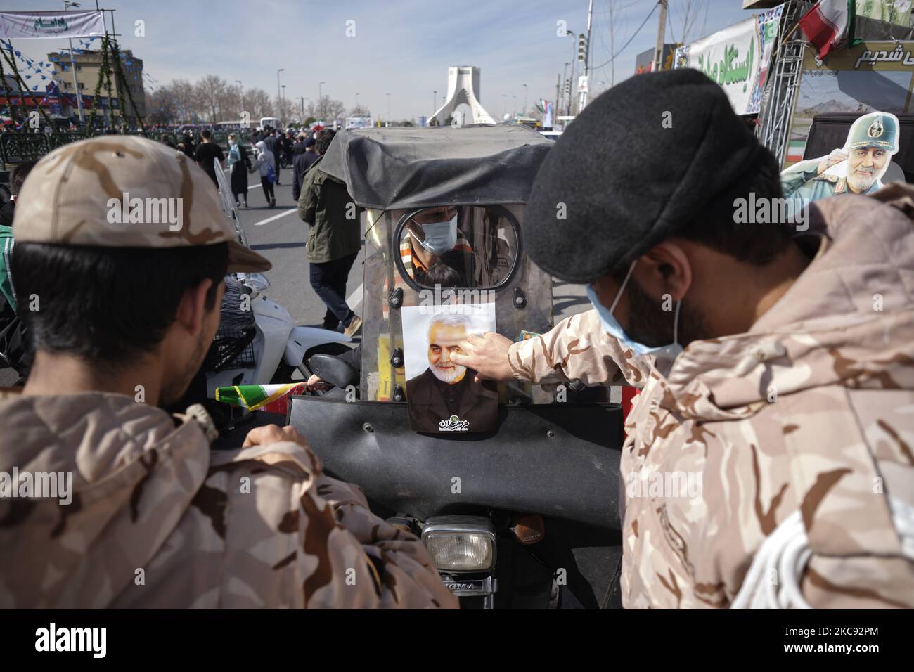 Ein Mitglied des IRGC klebt während einer Kundgebung zum Gedenken an den 42.. Jahrestag des Sieges der Islamischen Revolution ein Porträt des ehemaligen iranischen Kommandanten des Quds-Militärkorps der Islamischen Revolutionsgarde (IRGC), General Qasem Soleimani, auf die Windschutzscheibe eines Motorrads. Das fand am 10. Februar 2021 in der Azadi (Freedom) Avenue in Teheran mit Motorrädern unter dem Ausbruch der neuen Coronavirus-Krankheit (COVID-19) im Iran statt. (Foto von Morteza Nikoubazl/NurPhoto) Stockfoto