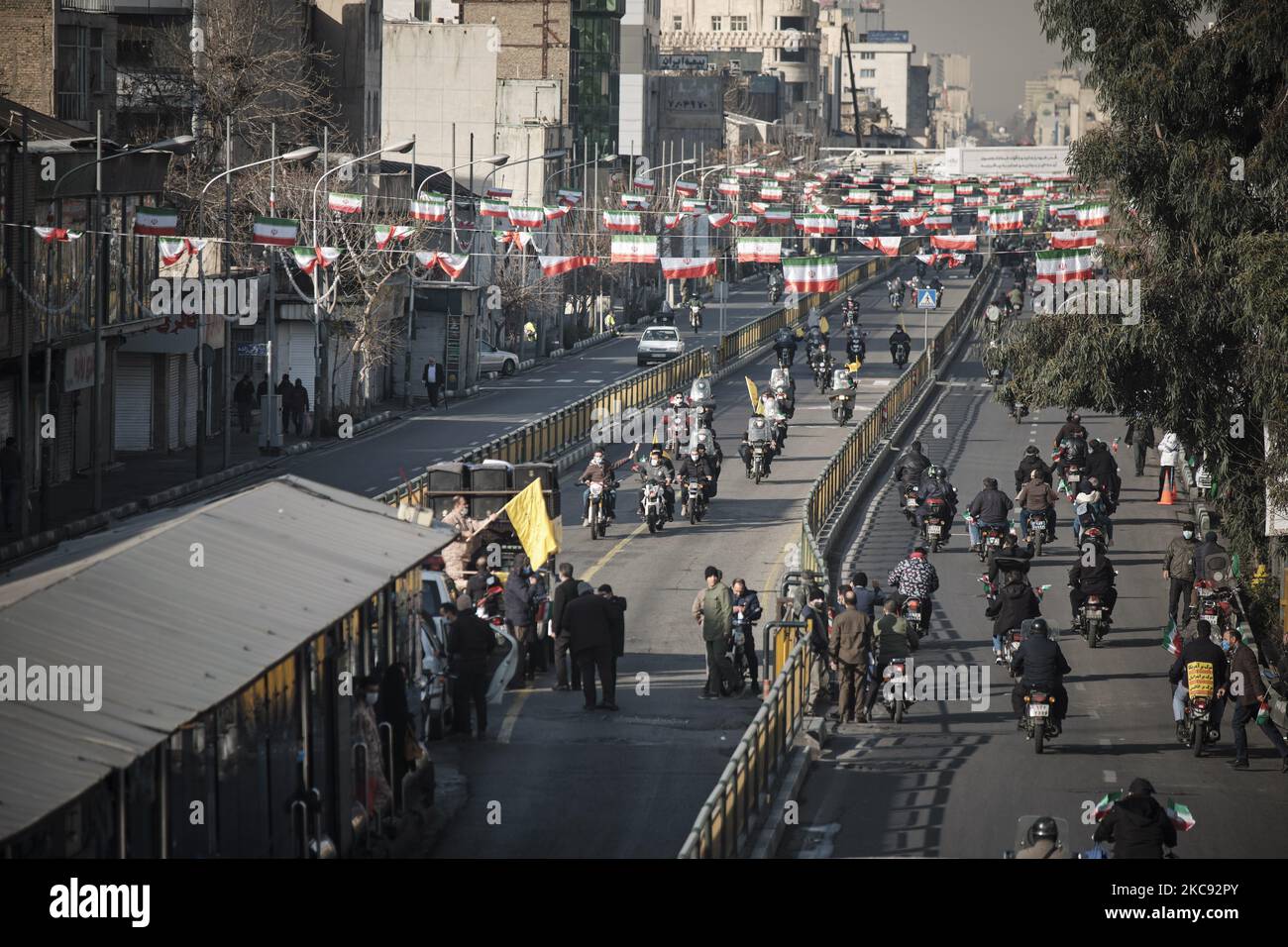 Iranische Motorradfahrer, die iranische Flaggen tragen, fahren auf der Enghelab-Straße (Revolution) entlang, während einer Kundgebung zum Gedenken an den 42.. Jahrestag des Sieges der Islamischen Revolution, die am 10. Februar 2021 mit Motorrädern inmitten des Ausbruchs der neuen Coronavirus-Krankheit (COVID-19) im Iran im Süden Teherans stattfand. (Foto von Morteza Nikoubazl/NurPhoto) Stockfoto